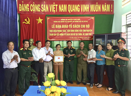Trung tá Hoàng Trọng Phước, Chỉ huy trưởng Ban CHQS huyện Châu Đức (thứ 6 từ phải qua) bàn giao tủ sách cho Chi bộ thôn Đồng Tâm.