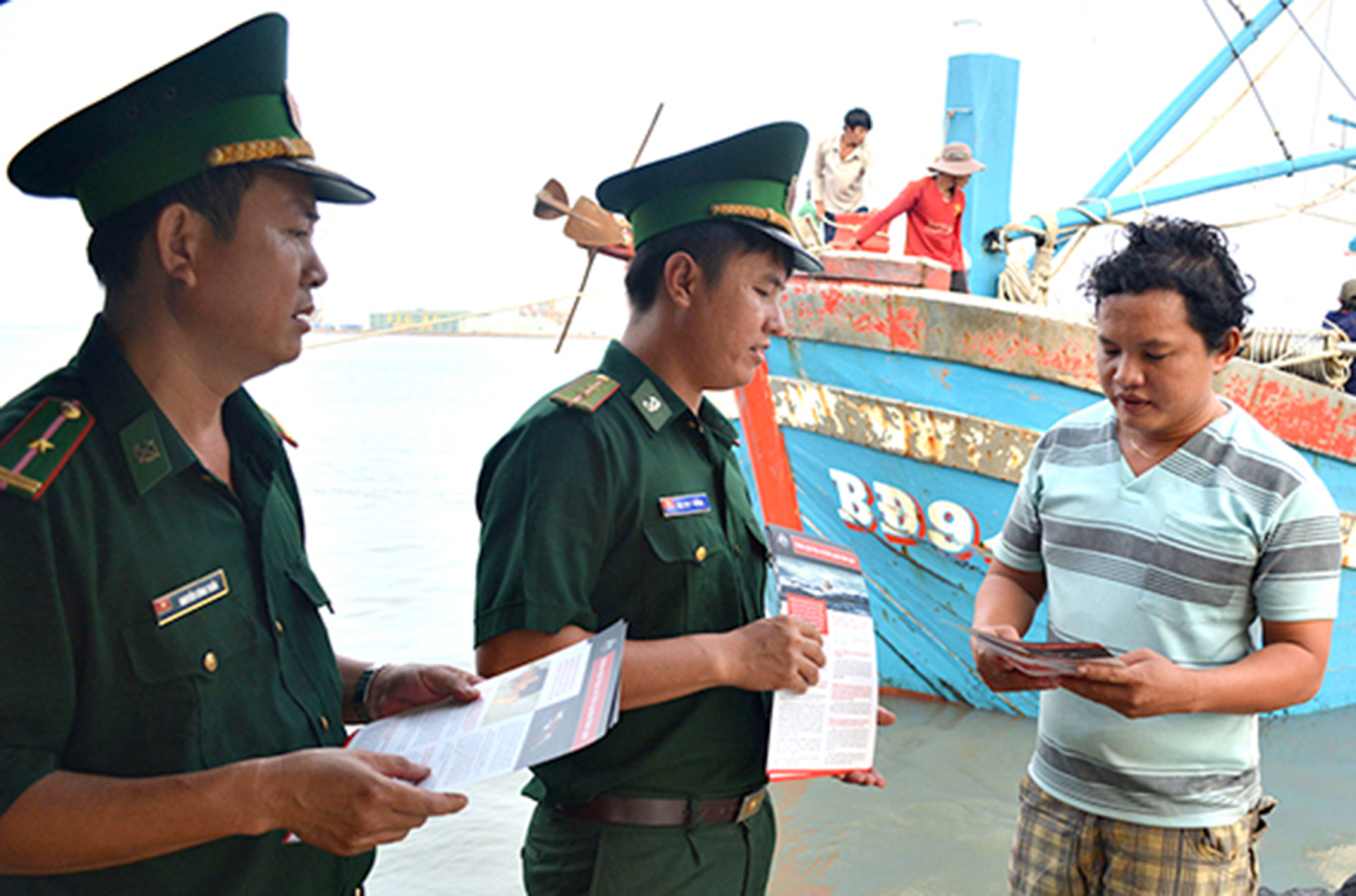 Cán bộ Đồn Biên phòng Bến Đá phát tờ rơi tuyên truyền, phổ biến giáo dục pháp luật cho bà con ngư dân.