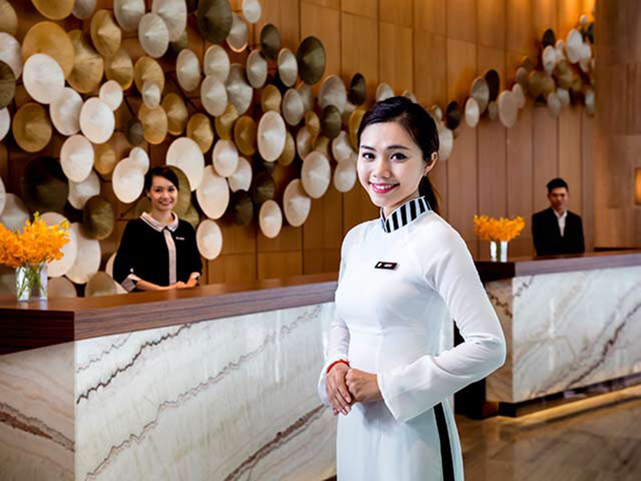 Lễ tân khách sạn 5 sao Pullman tươi cười chào đón khách.