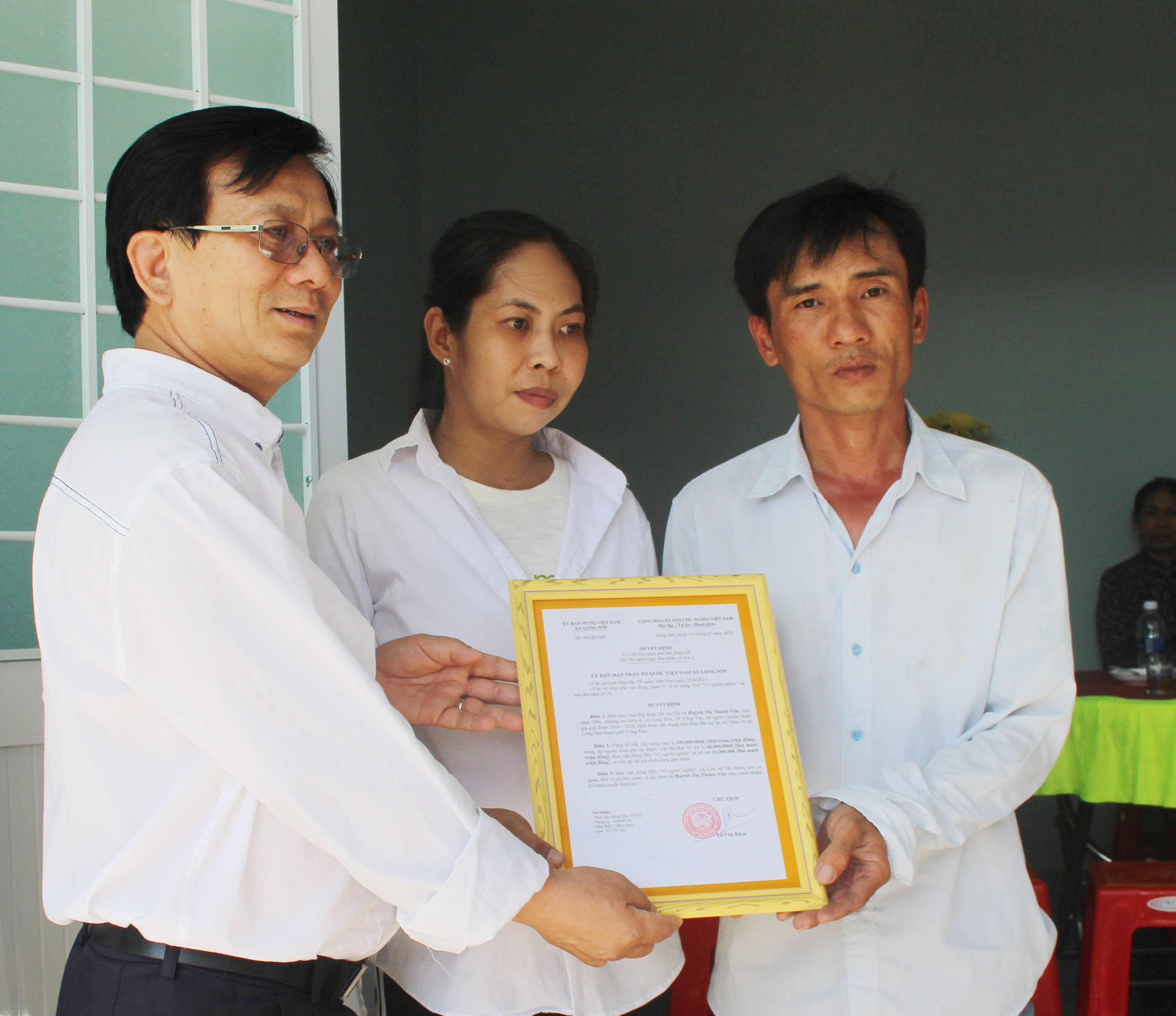 Bác sĩ Nguyễn Văn Hương, Giám đốc Bệnh viện Bà Rịa (bìa trái) trao quyết định bàn giao nhà đại đoàn kết cho vợ chồng bà Huỳnh Thị Thanh Vân.