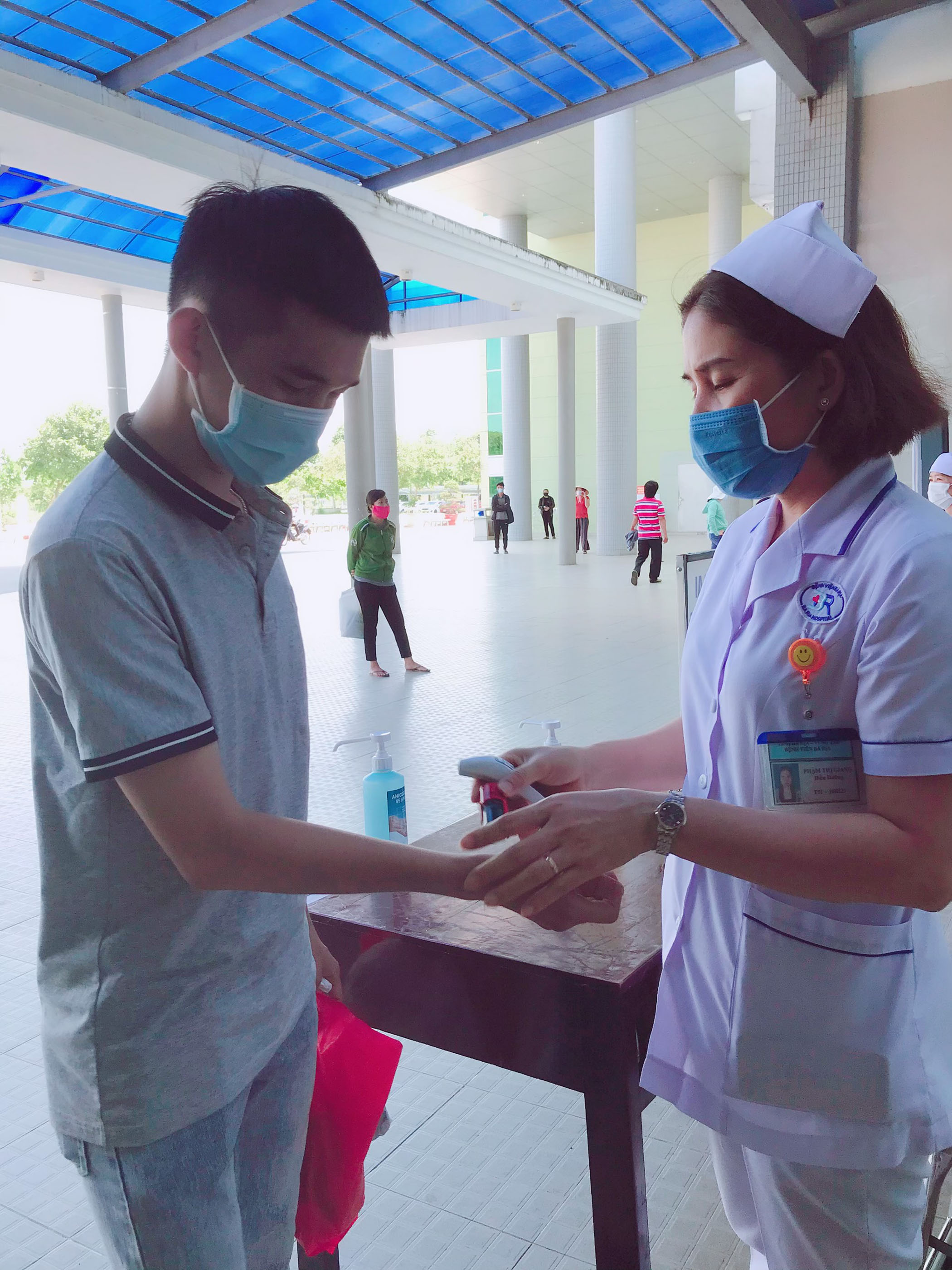 Nhân viên y tế Bệnh viện Bà Rịa đo thân nhiệt, đóng mộc đã sàng lọc vào tay bệnh nhân trước khi vào viện. Ảnh: HOÀNG HƯỜNG