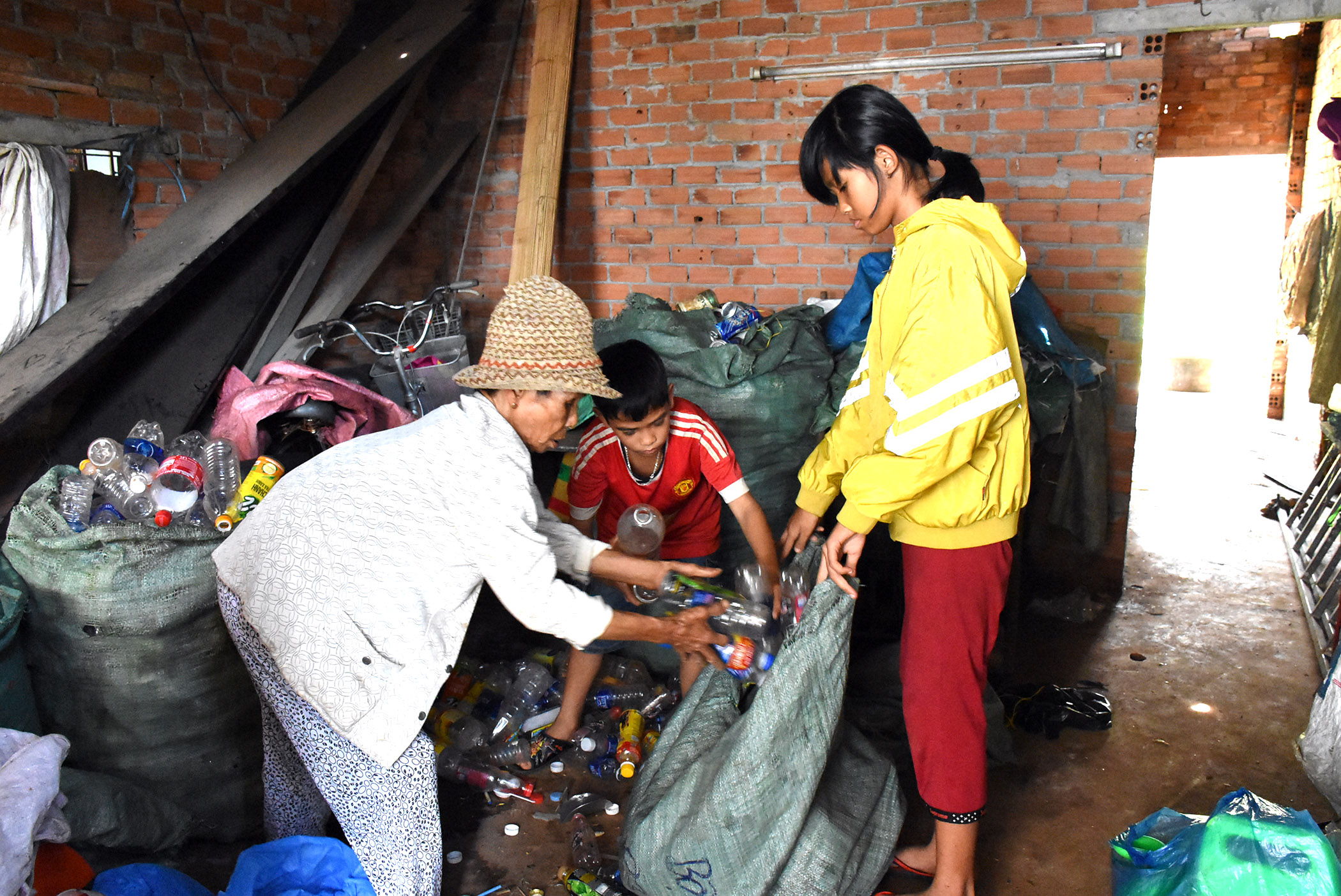 Các cháu phụ giúp bà phân loại ve chai để bán cho vựa có tiền trang trải cuộc sống.