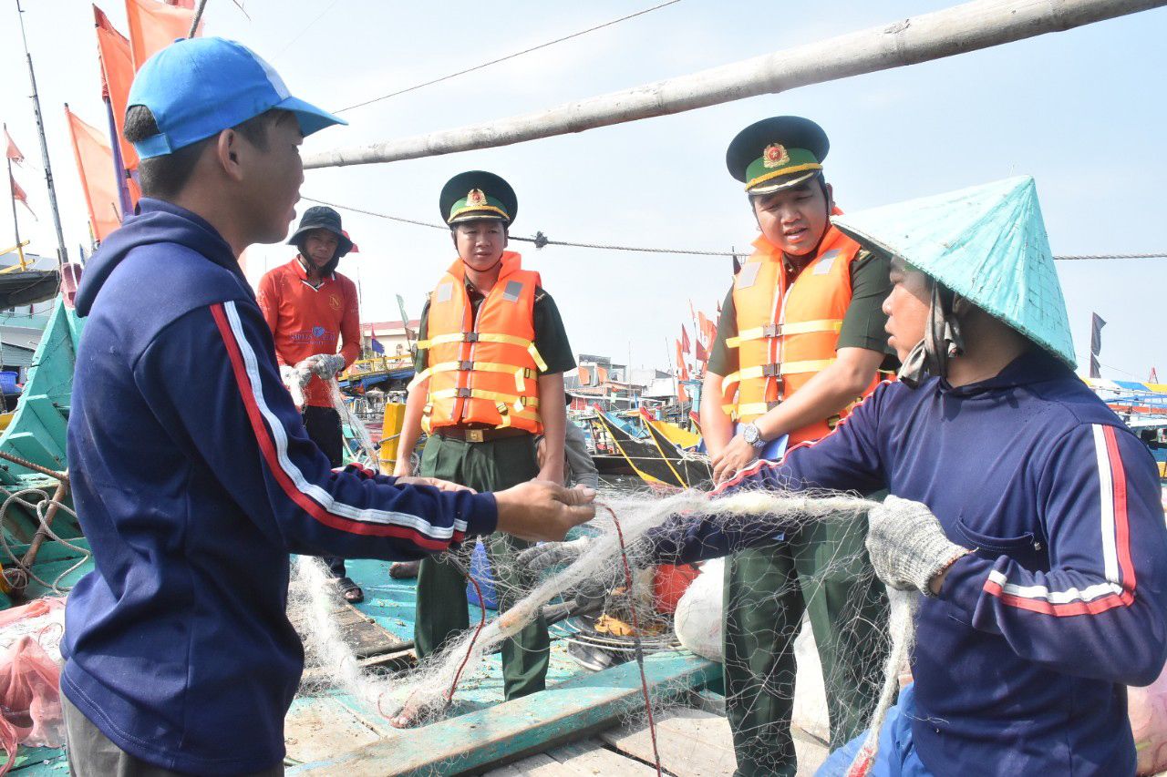Thiếu tá Phạm Hồng Quân (thứ hai, từ phải sang) tuyên truyền pháp luật cho ngư dân xã Phước Tỉnh.