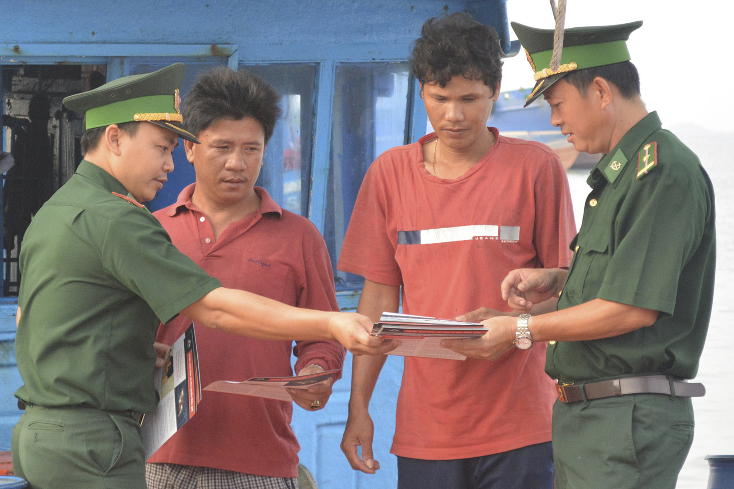 Cán bộ Đồn Biên phòng Bến Đá phát tờ rơi tuyên truyền, phổ biến giáo dục pháp luật về biển đảo cho bà con ngư dân. Ảnh: PHƯƠNG NAM