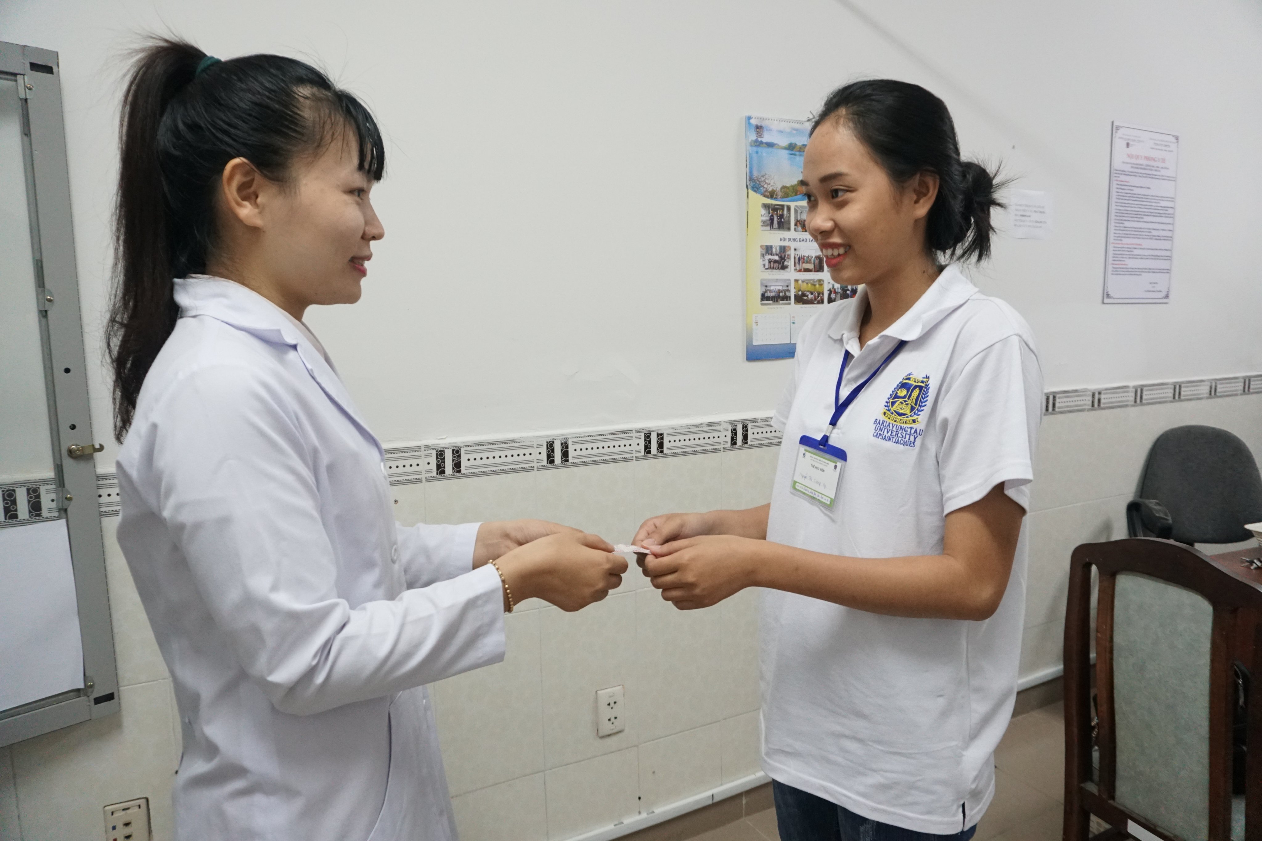 Nhân viên y tế Trường Đại học BR-VT trao thẻ BHYT cho sinh viên.
