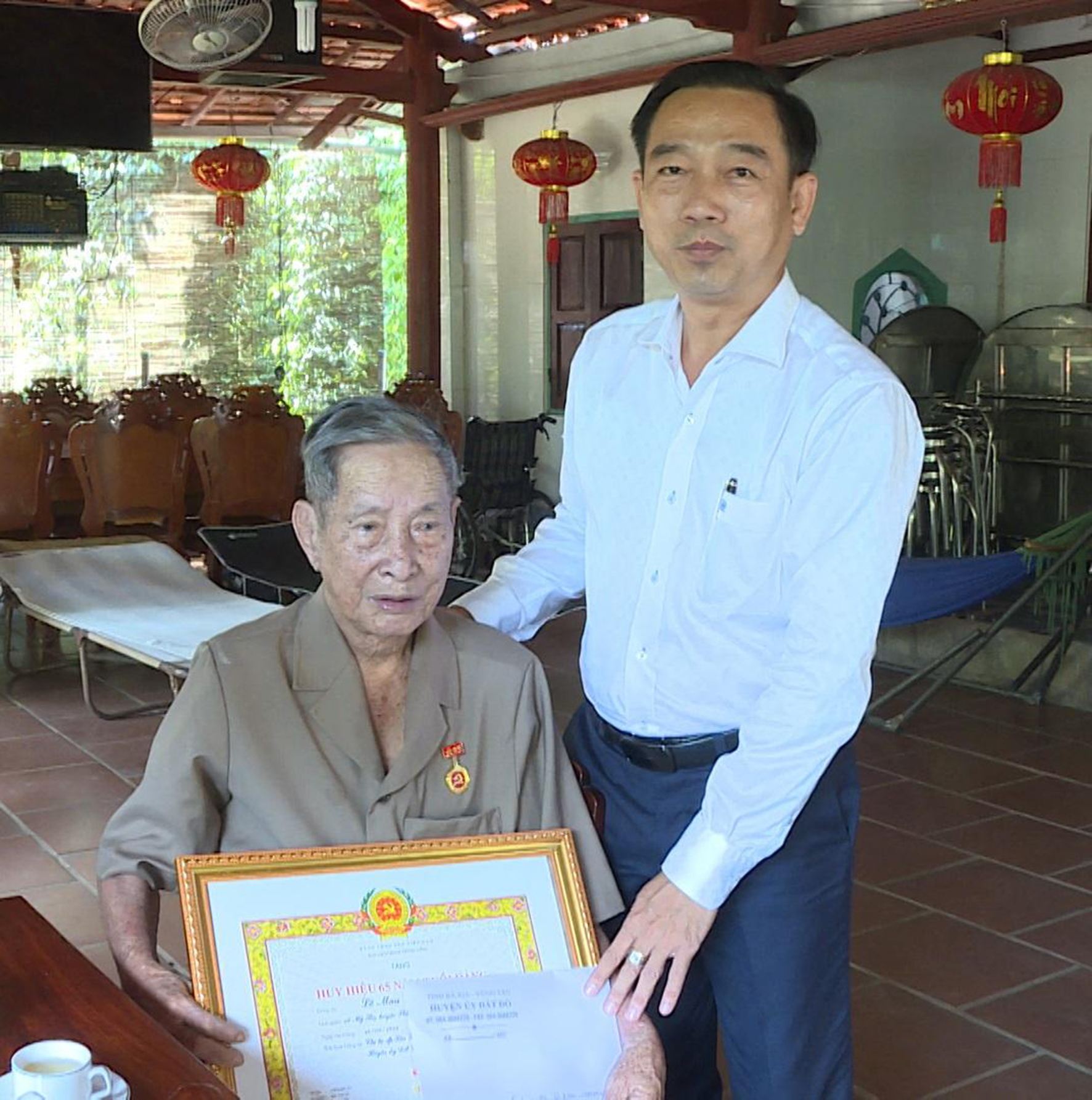 Ông Lê Văn Hòa, Bí thư Huyện ủy Đất Đỏ trao Huy hiệu 65 năm tuổi Đảng cho đảng viên lão thành Lê Mau. Ảnh: TUẤN VŨ