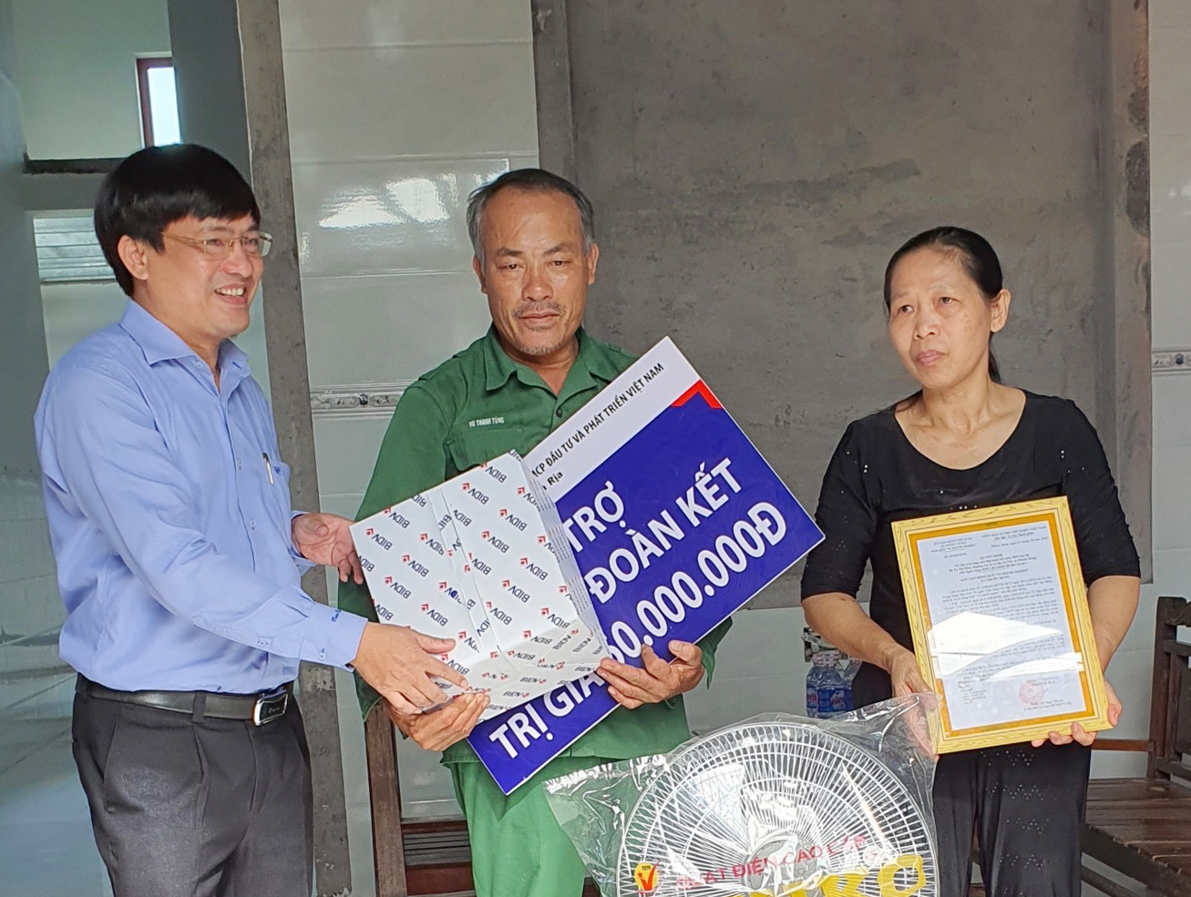 Ông Trần Văn Nhân (trái), Phó Giám đốc Ngân hàng BIDV chi nhánh Bà Rịa tặng quà, quạt điện cho gia đình bà Tạ Thị Màu.