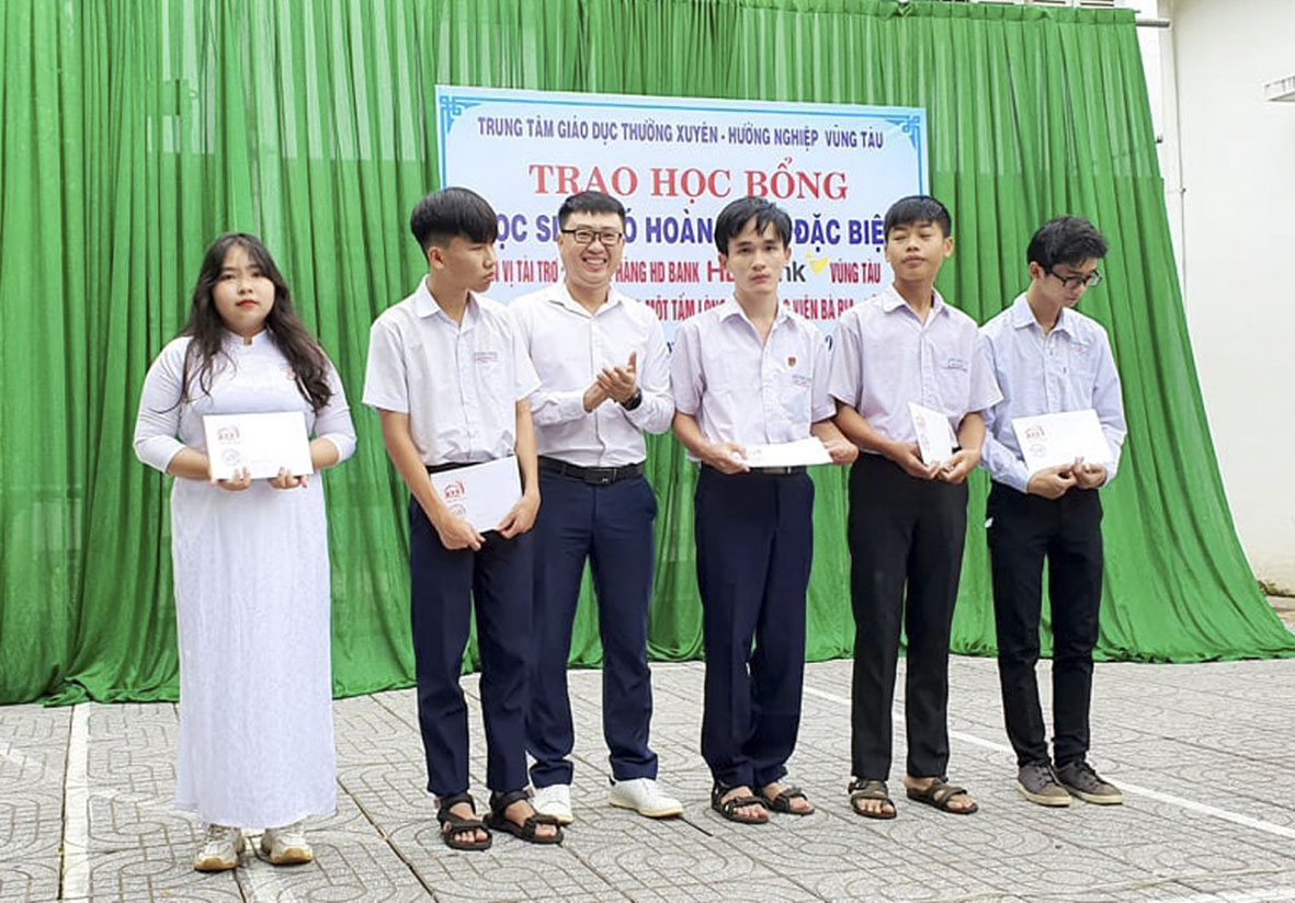 Đại diện Quỹ chung một tấm lòng - CLB phóng viên BR- VT (thứ ba từ trái sang) trao thẻ BHYT cho HS.