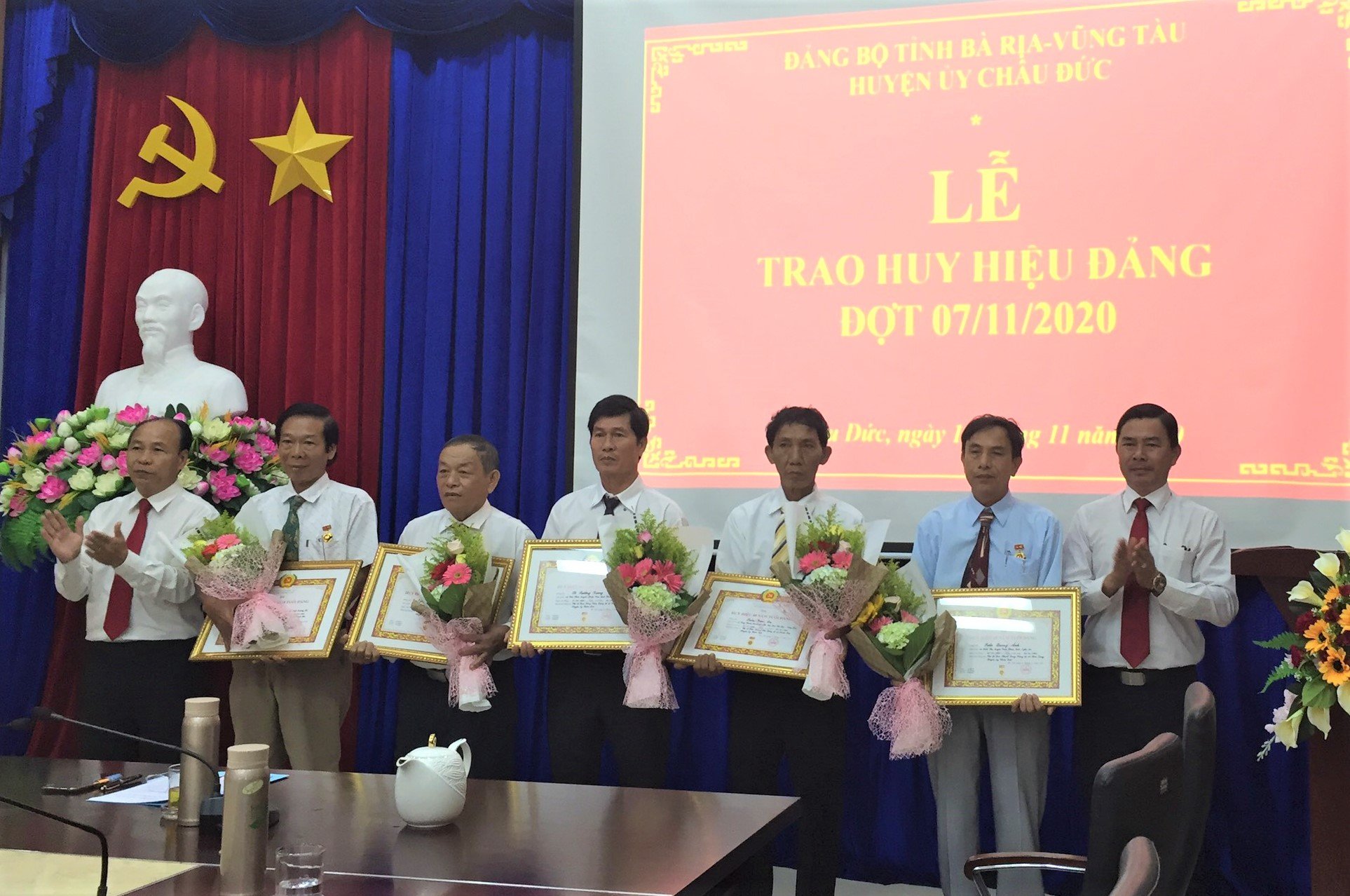 ông Nguyễn Văn Việt, Bí thư Huyện ủy Châu Đức (ngoài cùng bên trái) và ông Lê Binh, Chủ tịch UBMTTQVN huyện (ngoài cùng bên phải) trao Huy hiệu 40 năm tuổi Đảng cho các đảng viên tại buổi lễ
