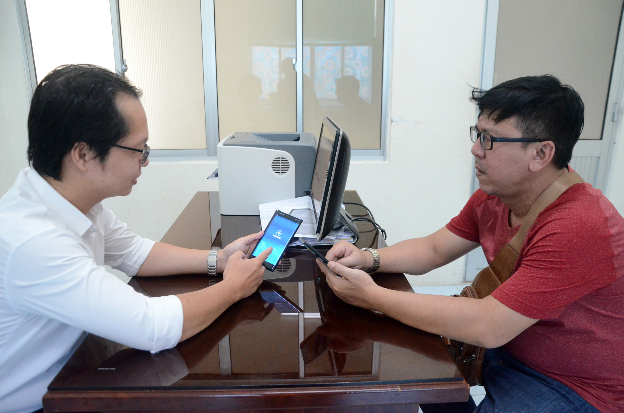 Nhân viên Điện lực Vũng Tàu hướng dẫn khách hàng cài đặt App chăm sóc khách hàng của ngành điện trên điện thoại.