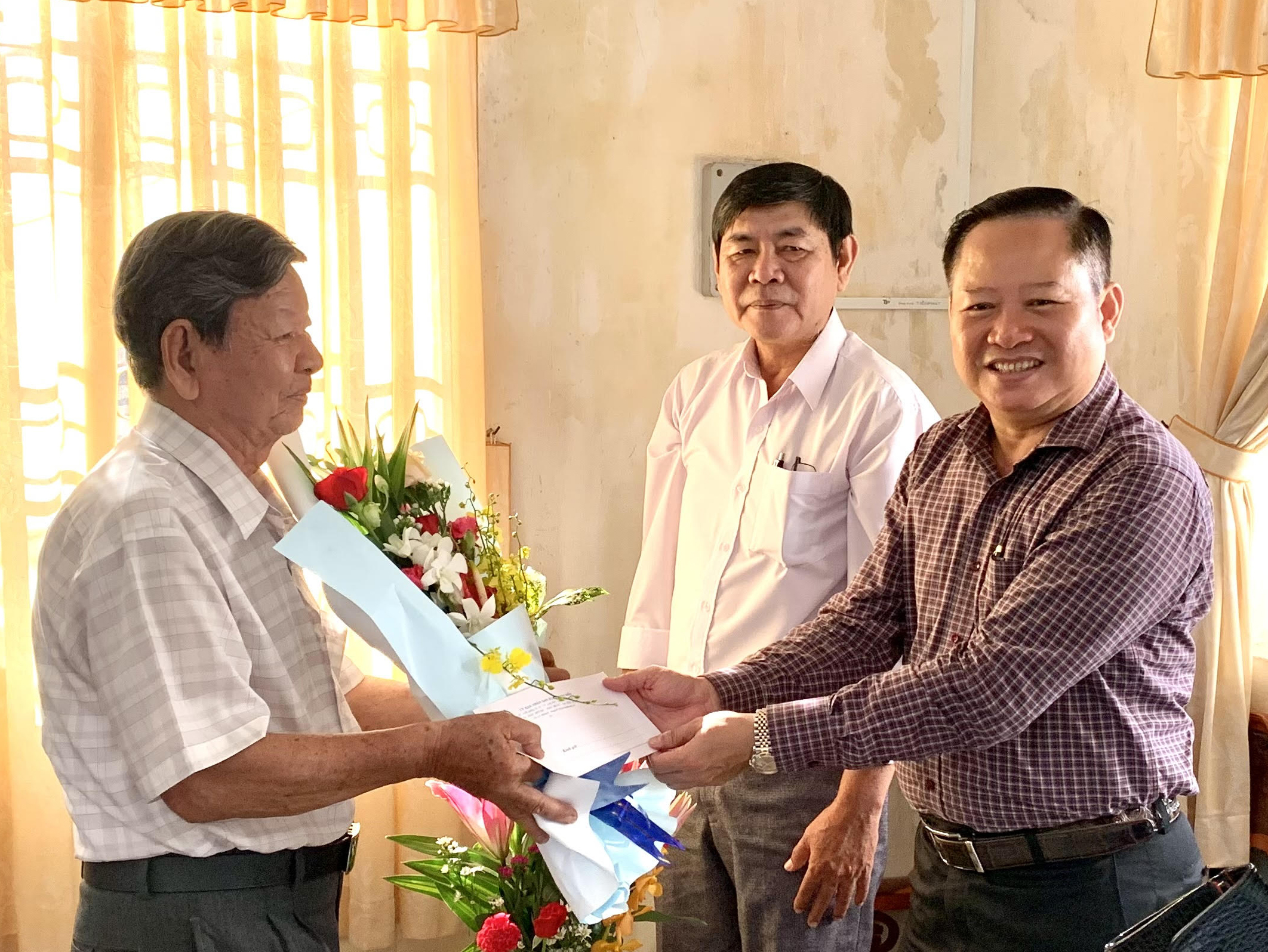 Ông Lê Ngọc Linh (phải), Bí thư Huyện ủy Long Điền, tặng hoa và quà cho nhà giáo Nguyễn Thế  Khải.