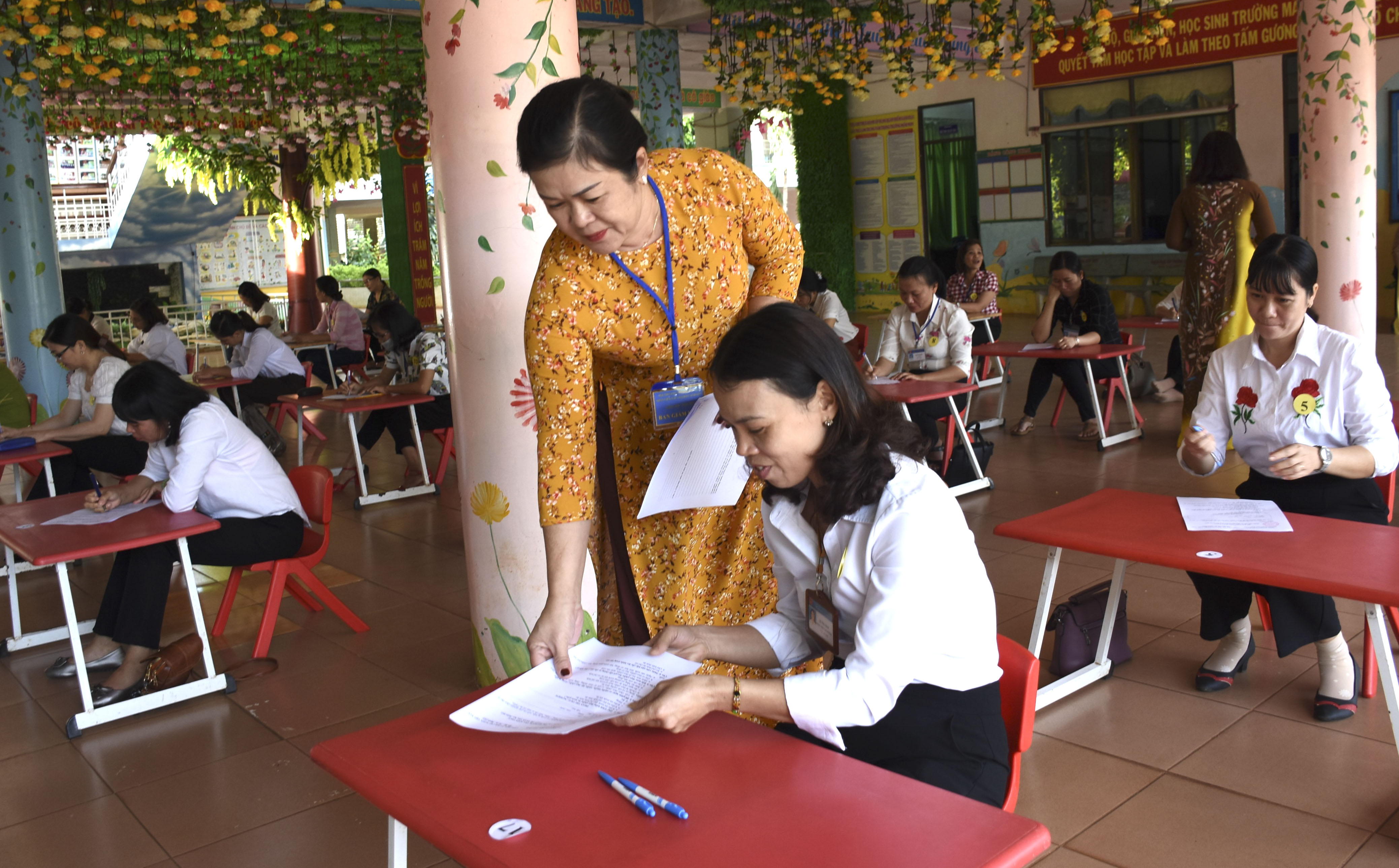 Ban giám khảo phát đề thi trắc nghiệm cho các nhân viên MN.