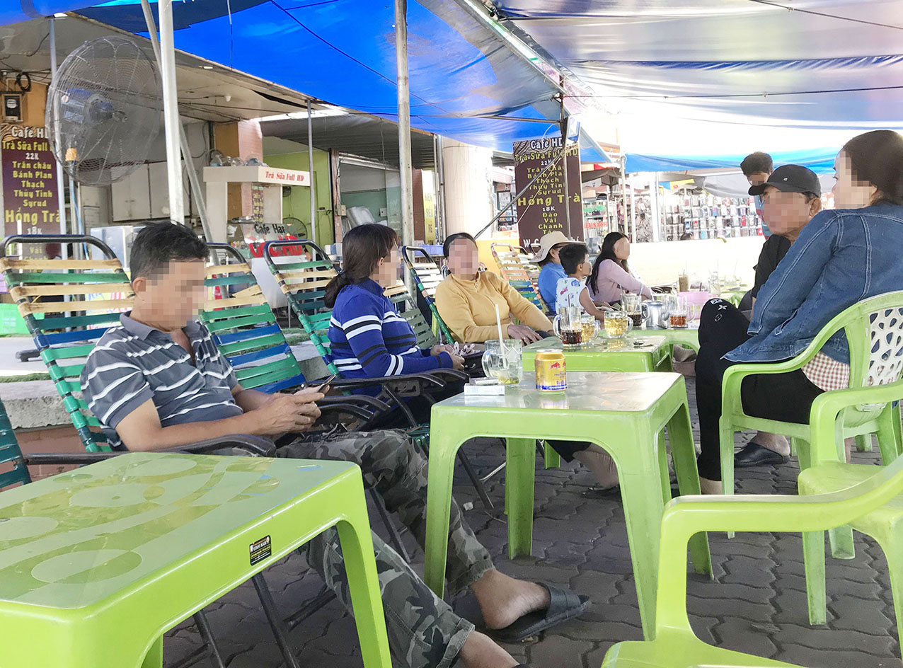 Nhóm khách uống cà phê trước cổng Trung tâm thương mại Bà Rịa sáng 3/12. Chủ quán, nhân viên và khách đều không đeo khẩu trang.