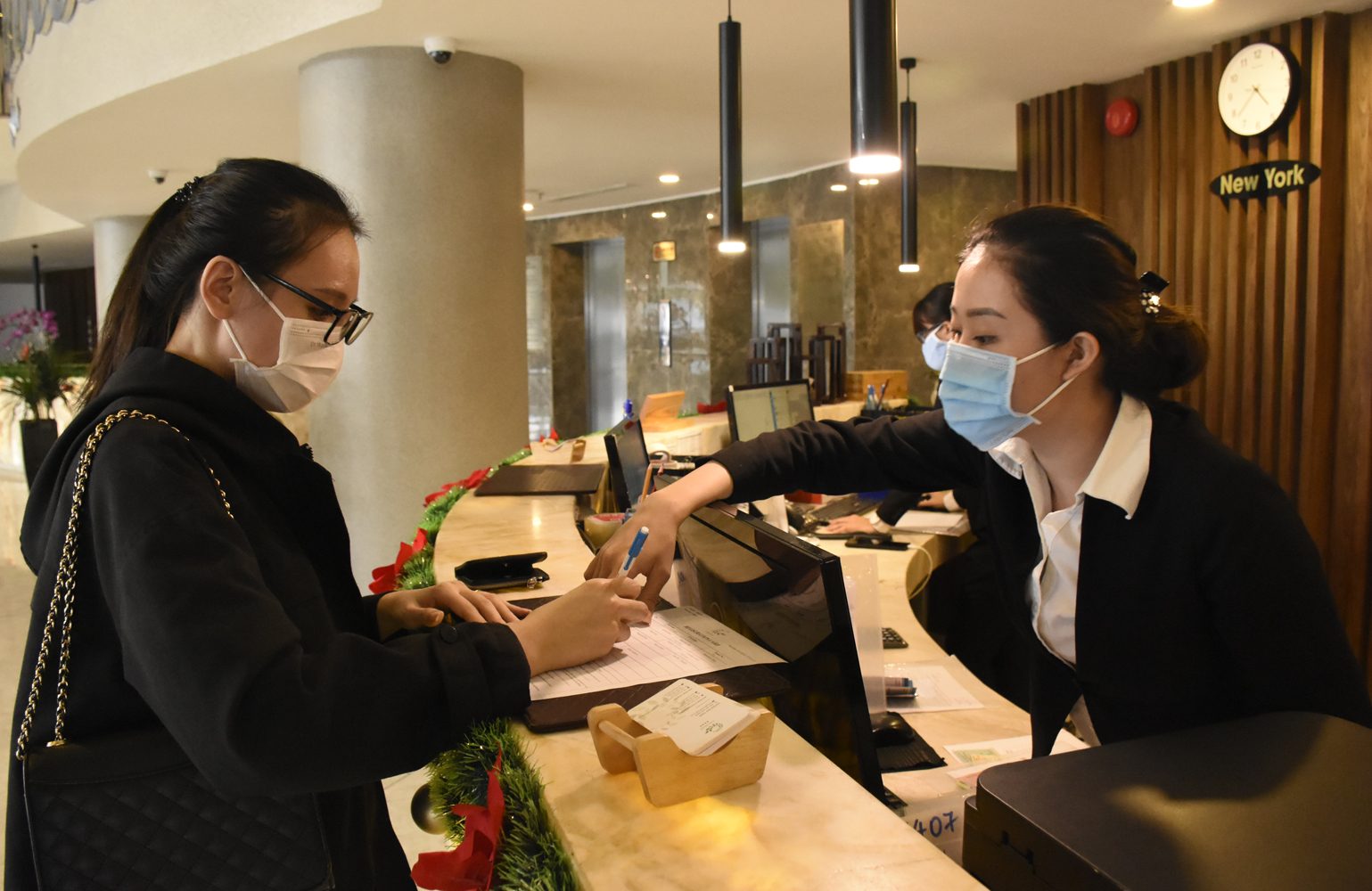 Các cơ sở lưu trú đều kích hoạt các giải pháp phòng dịch.  Trong ảnh: Nhân viên khách sạn CAO hướng dẫn du khách làm thủ tục nhận phòng. 