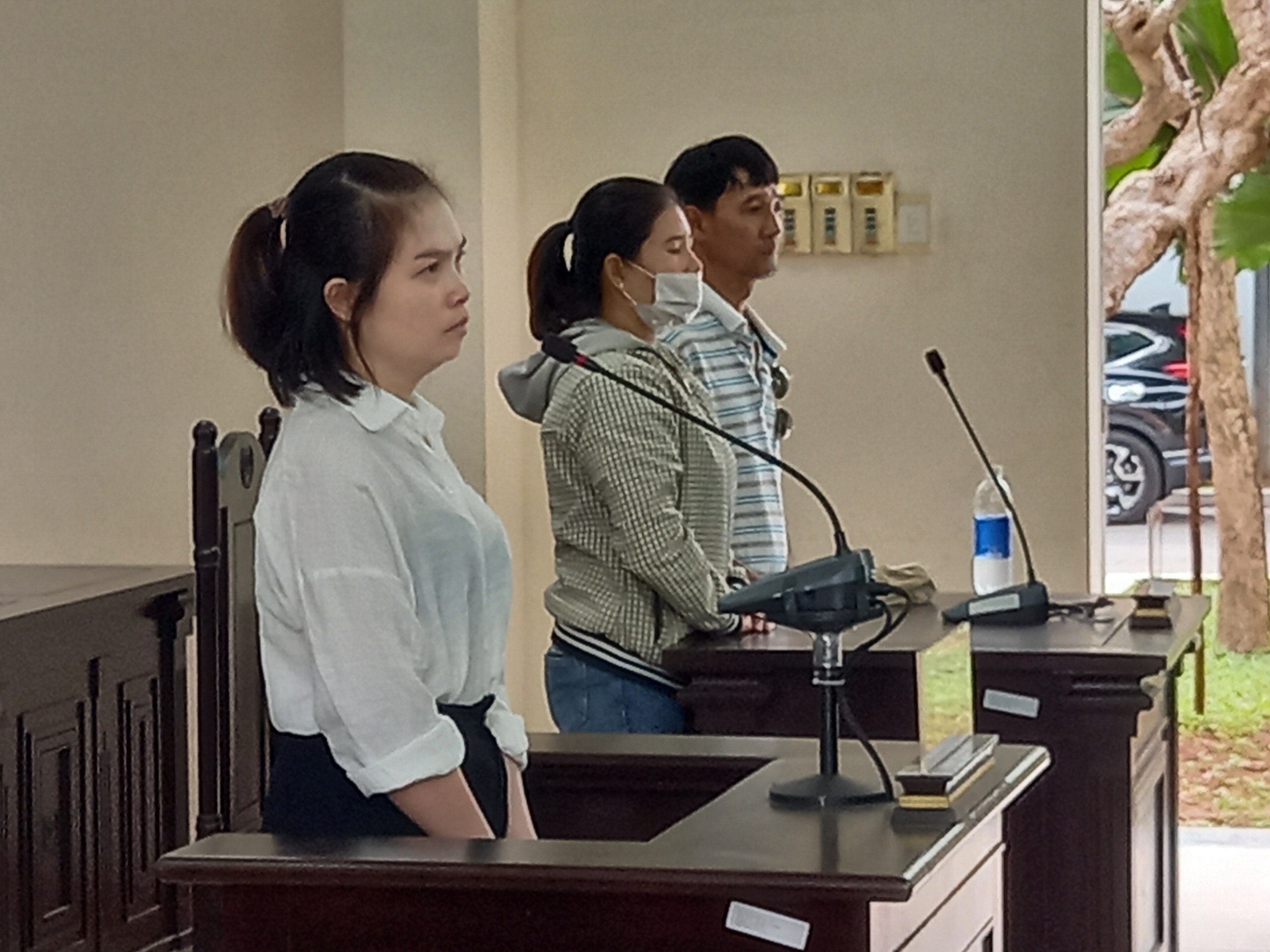 Bị cáo Trần Thị Trà My (bên trái) tại phiên tòa sơ thẩm và vợ chồng bị hại.