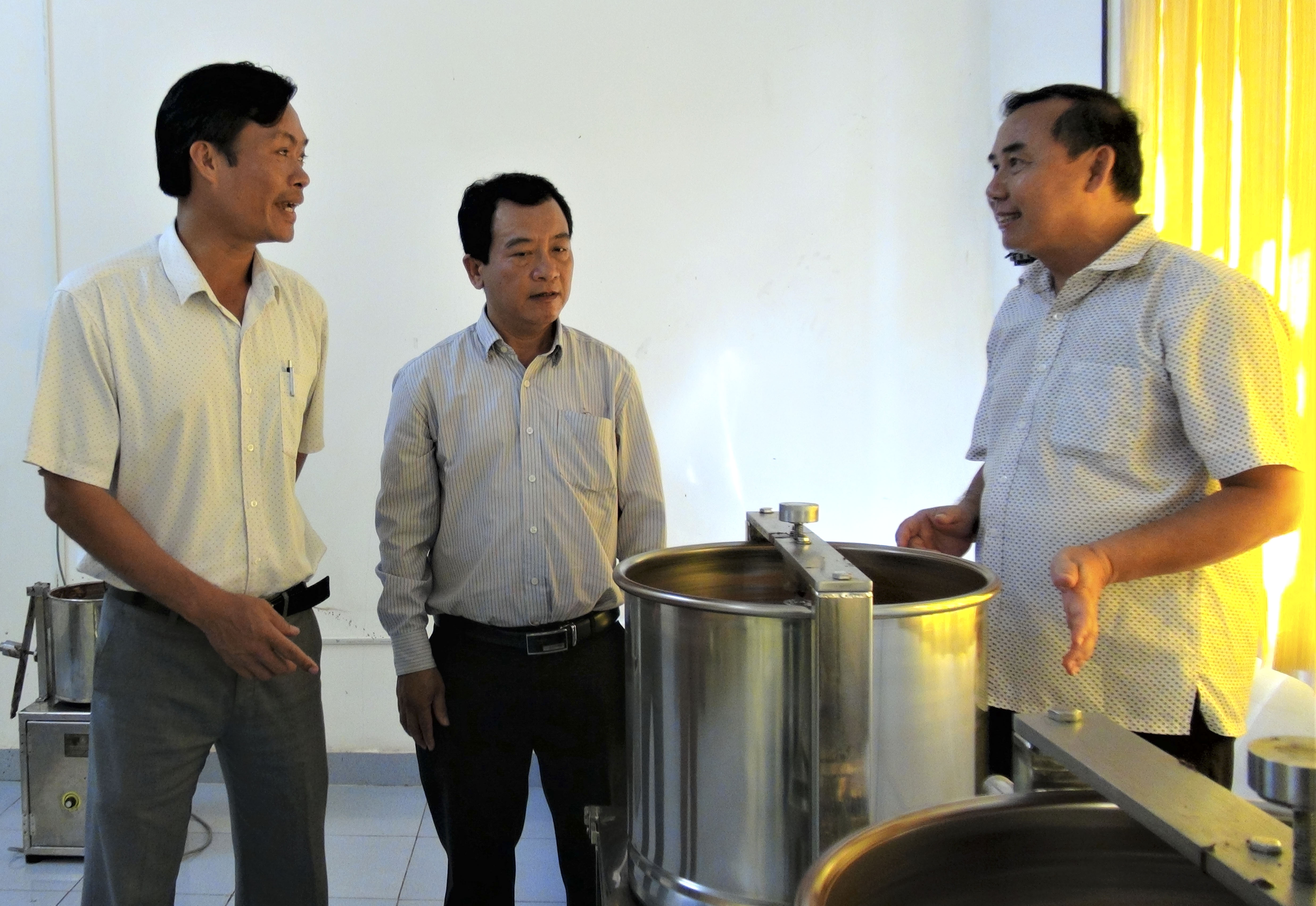 Ông Trịnh Văn Thành, Giám đốc Công ty TNHH TM - DV - SX ca cao Thành Đạt (bìa phải) giới thiệu quy trình chế biến chocolate cho các đại biểu đến dự lễ xuất khẩu lô hàng đầu tiên sang Nhật Bản.