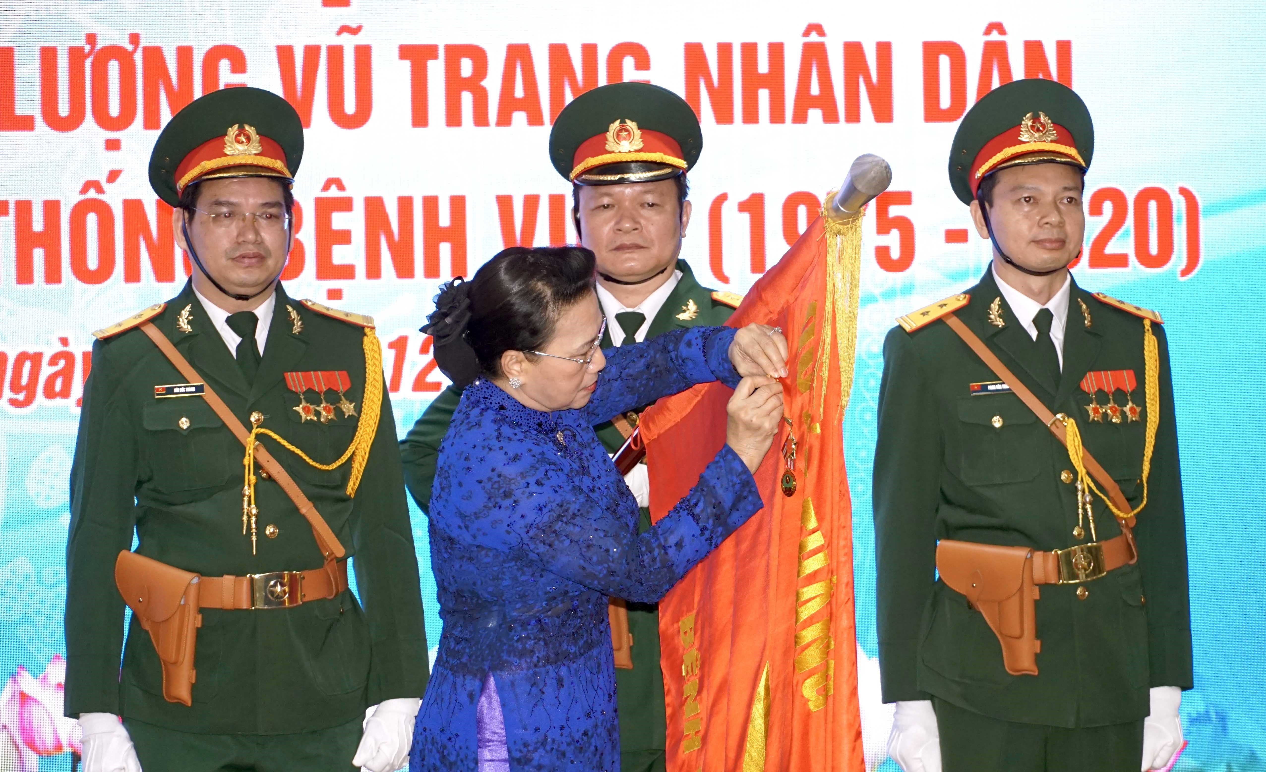 Chủ tịch Quốc hội Nguyễn Thị Kim Ngân gắn danh hiệu Anh hùng Lực lượng vũ trang nhân dân lên lá cờ truyền thống Bệnh viện Quân y 175. Ảnh: XUÂN KHU