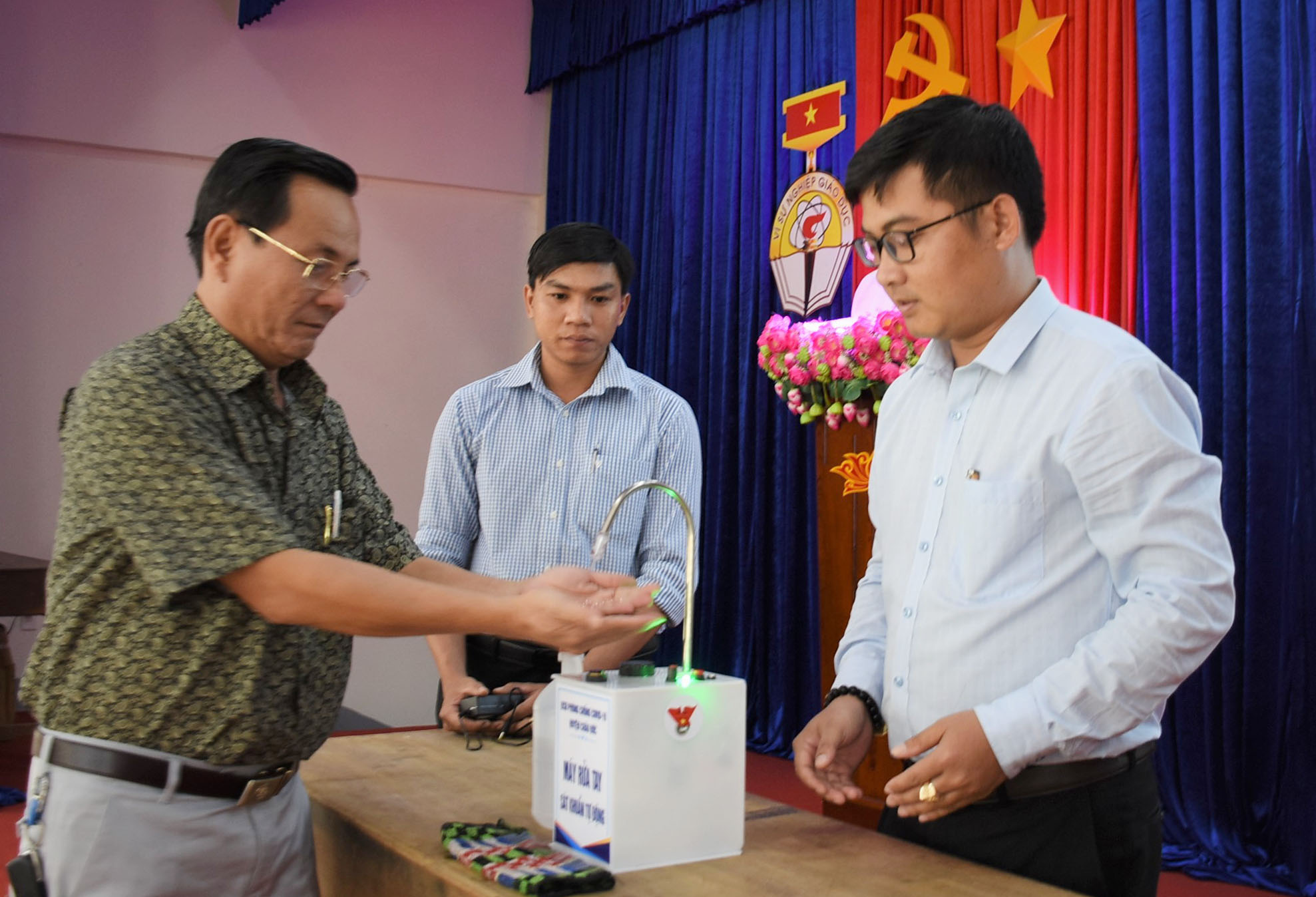 Đoàn viên thanh niên hướng dẫn giáo viên sử dụng máy rửa tay sát khuẩn.