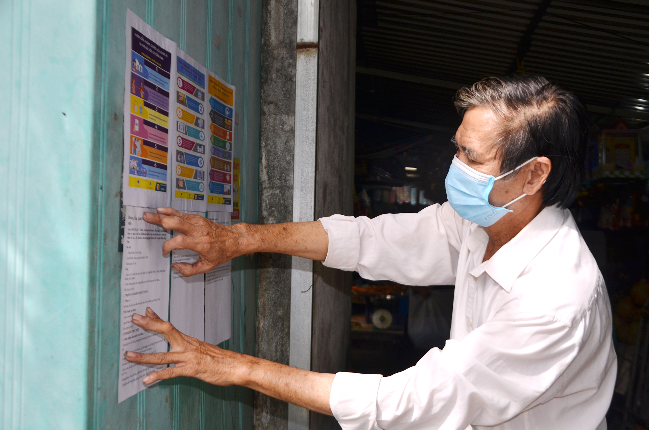 Ông Trần Ngọc Thành, Trưởng BQL Chợ Tân Thành, TX.Phú Mỹ dán thông tin liên quan đến COVID-19 tại các vị trí dễ nhìn trong chợ để tiểu thương và người dân chú ý đọc. Ảnh: DIỄM QUỲNH