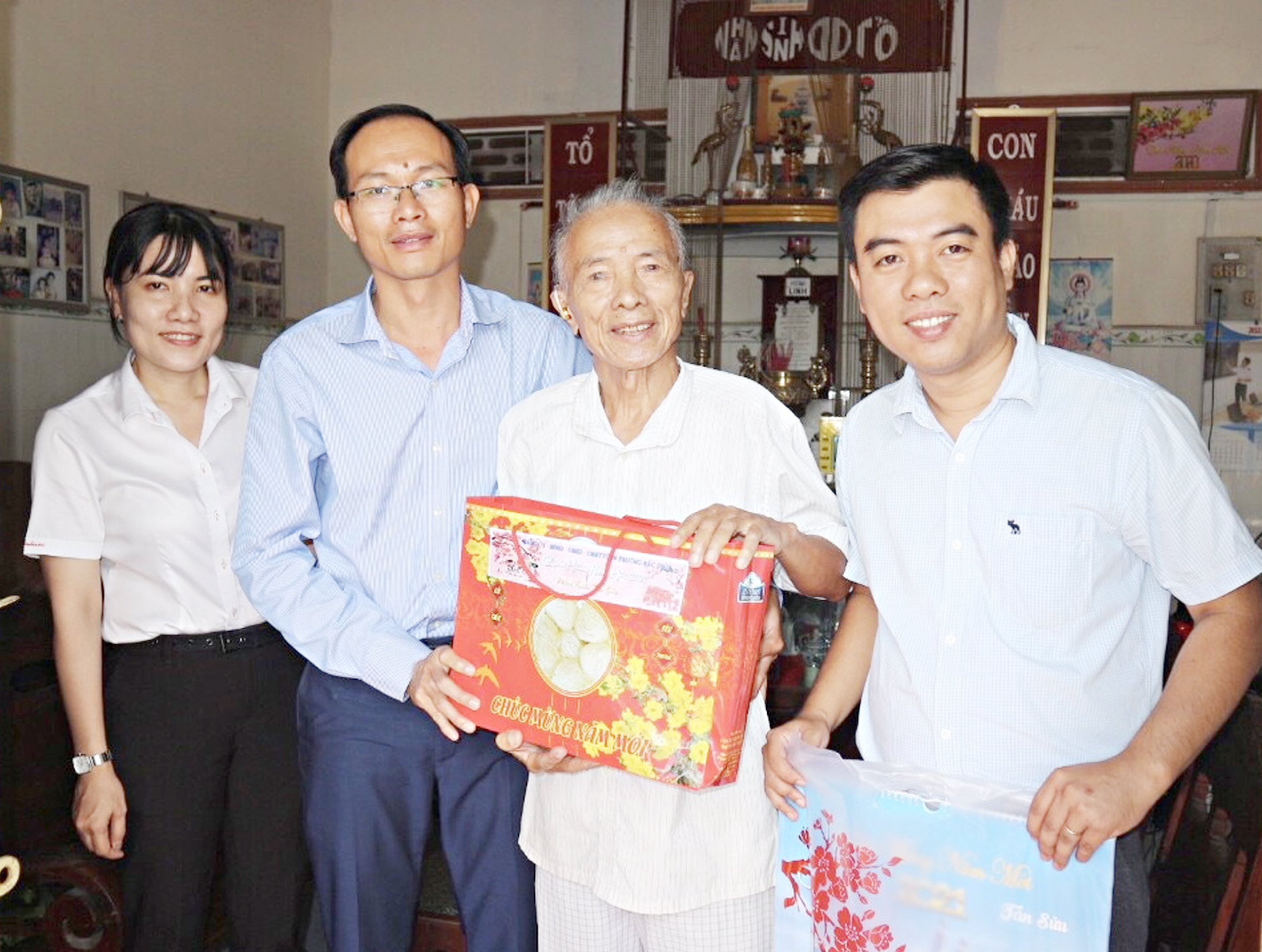 Ông Phan Minh Hợp, Bí thư Đảng ủy phường Hắc Dịch (thứ 2, từ trái qua) thăm hỏi, tặng quà Tết ông Đặng Duy Bình (50 tuổi Đảng, ở khu phố 2).