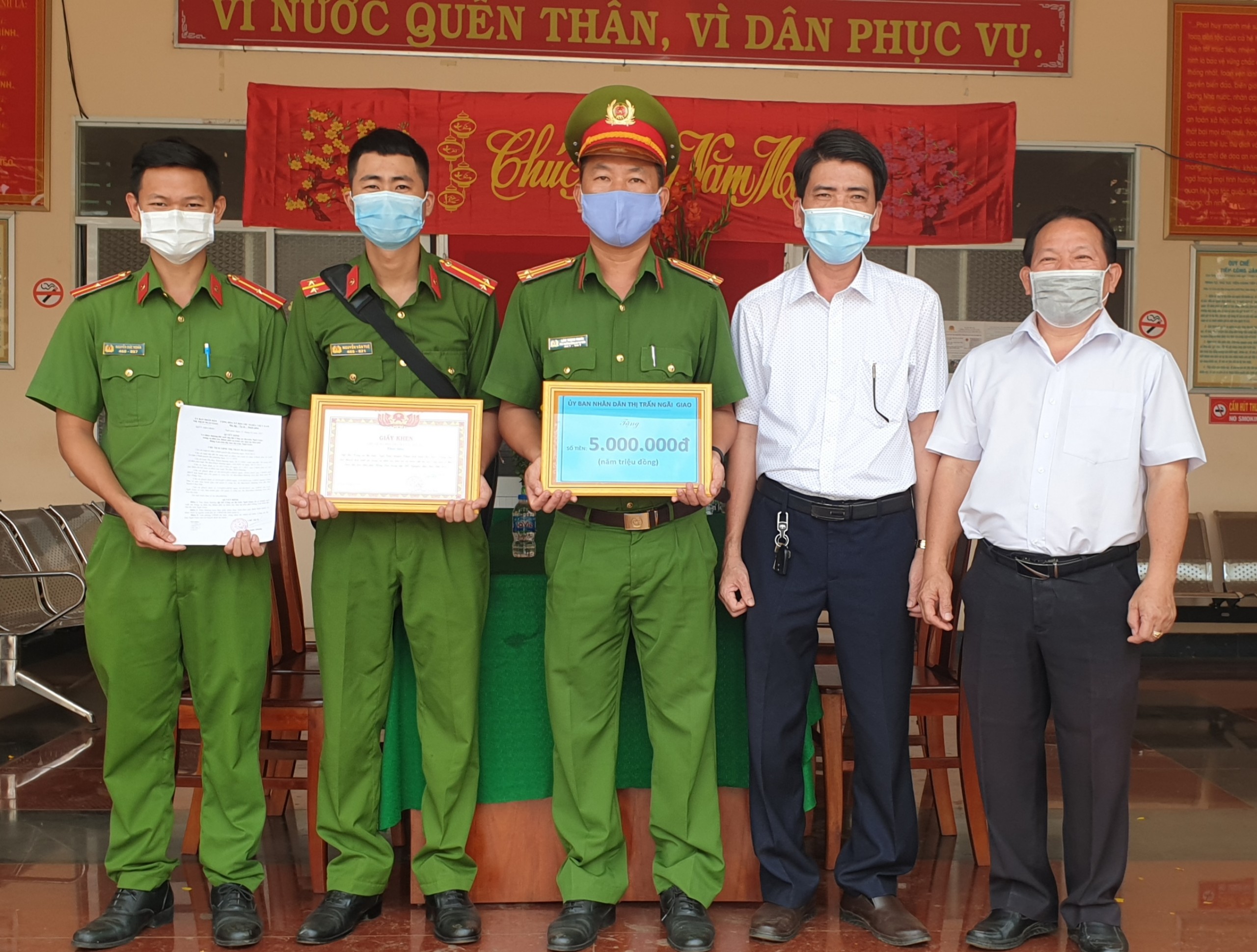 Bí thư Đảng ủy thị trấn Nguyễn Hồng Hà (bìa phải) và ông Nguyễn Xuân Quang Chủ tịch UBND thị trấn Ngãi Giao khen thưởng cho các chiến sĩ Công an đã phá án nhanh. 