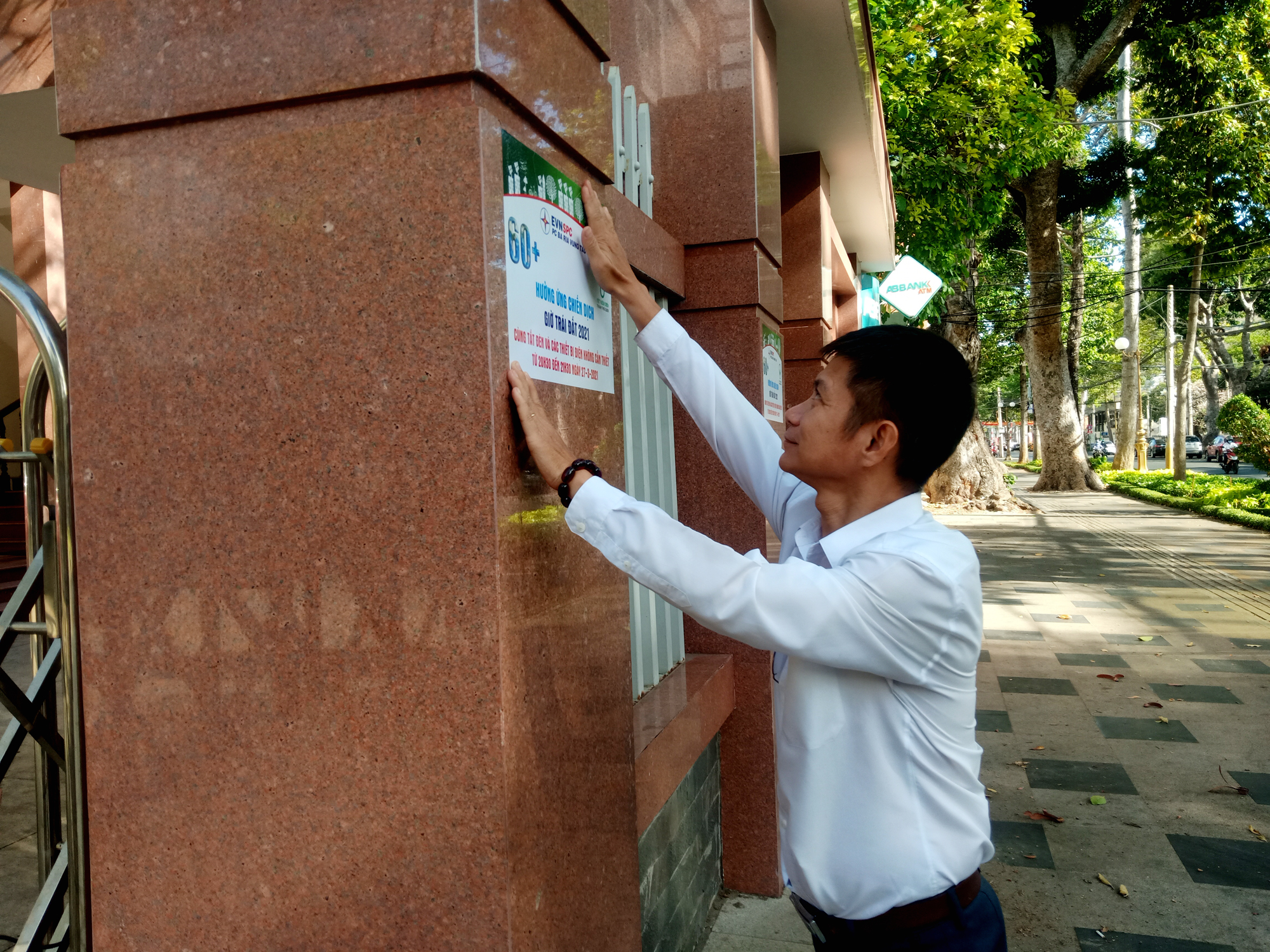 Nhân viên Công ty Điện lực BR-VT dán poster tuyên truyền về sự kiện Giờ Trái đất 2021 tại cổng Công ty.