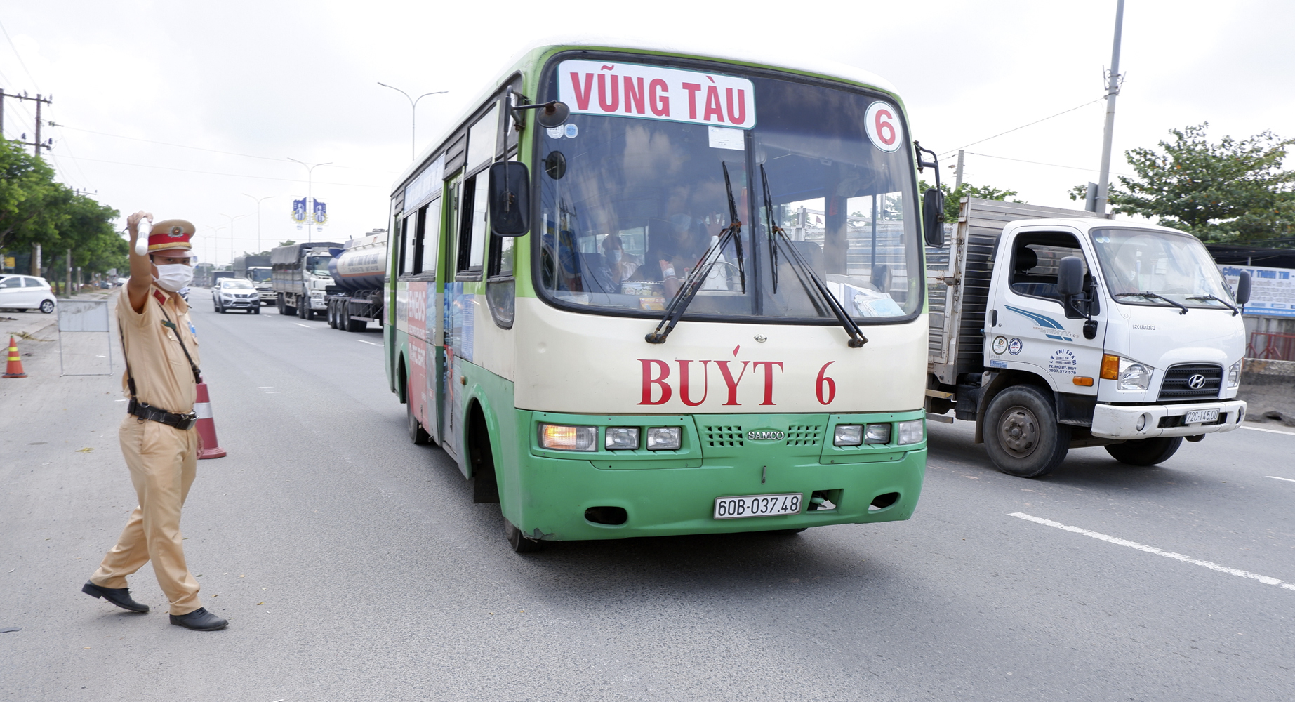 CSGT ra hiệu lệnh yêu cầu xe buýt vào Chốt kiểm kiểm tra liên ngành phòng, chống dịch trên QL51 để hành khách vào khai báo y tế, kiểm tra thân nhiệt. Ảnh: MINH HƯƠNG