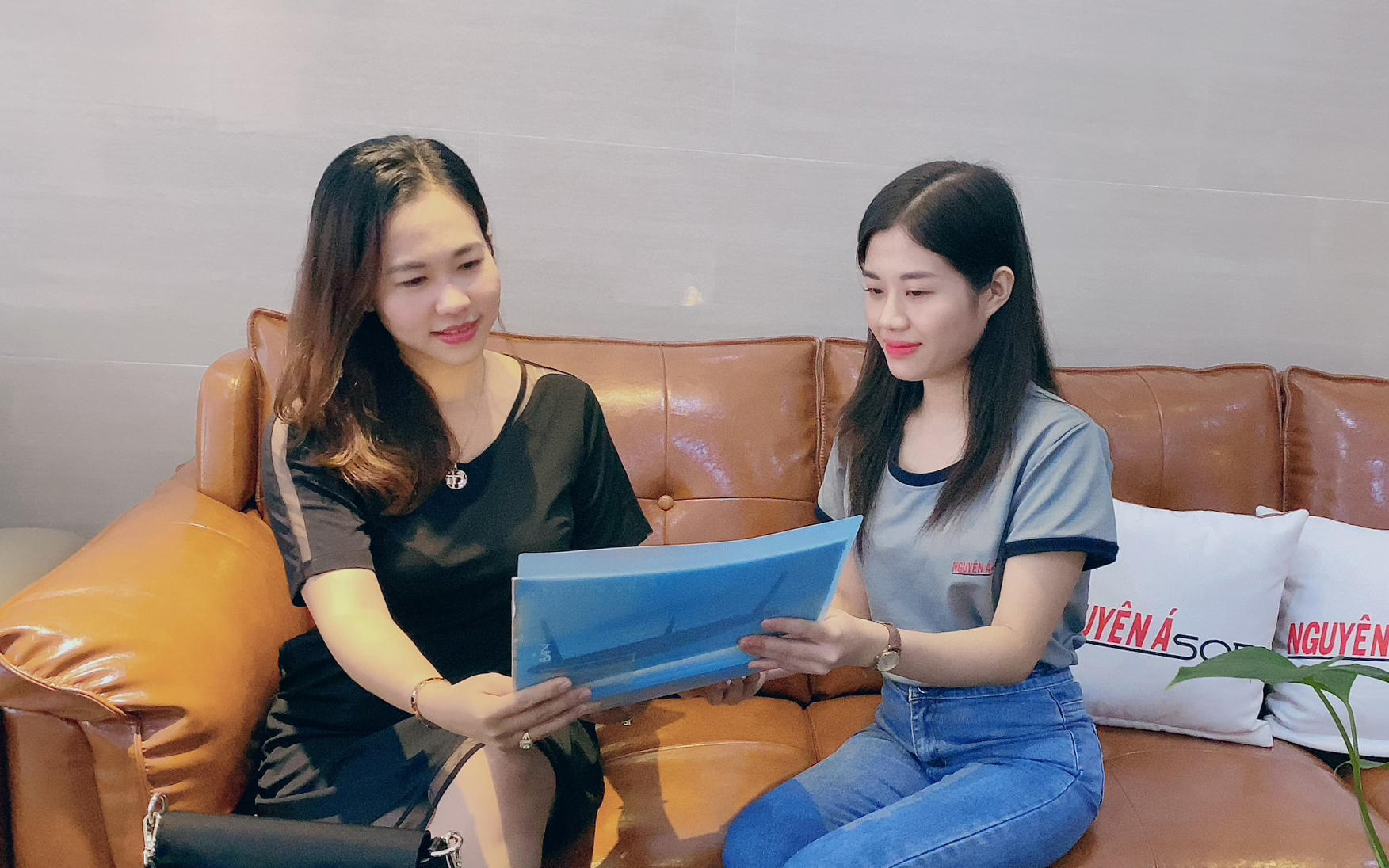 Chị Ong Thị Thanh Nguyệt, Giám đốc Công ty Nội thất Nguyên Á (trái) trao đổi các sản phẩm mới trên cataloge với nhân viên.