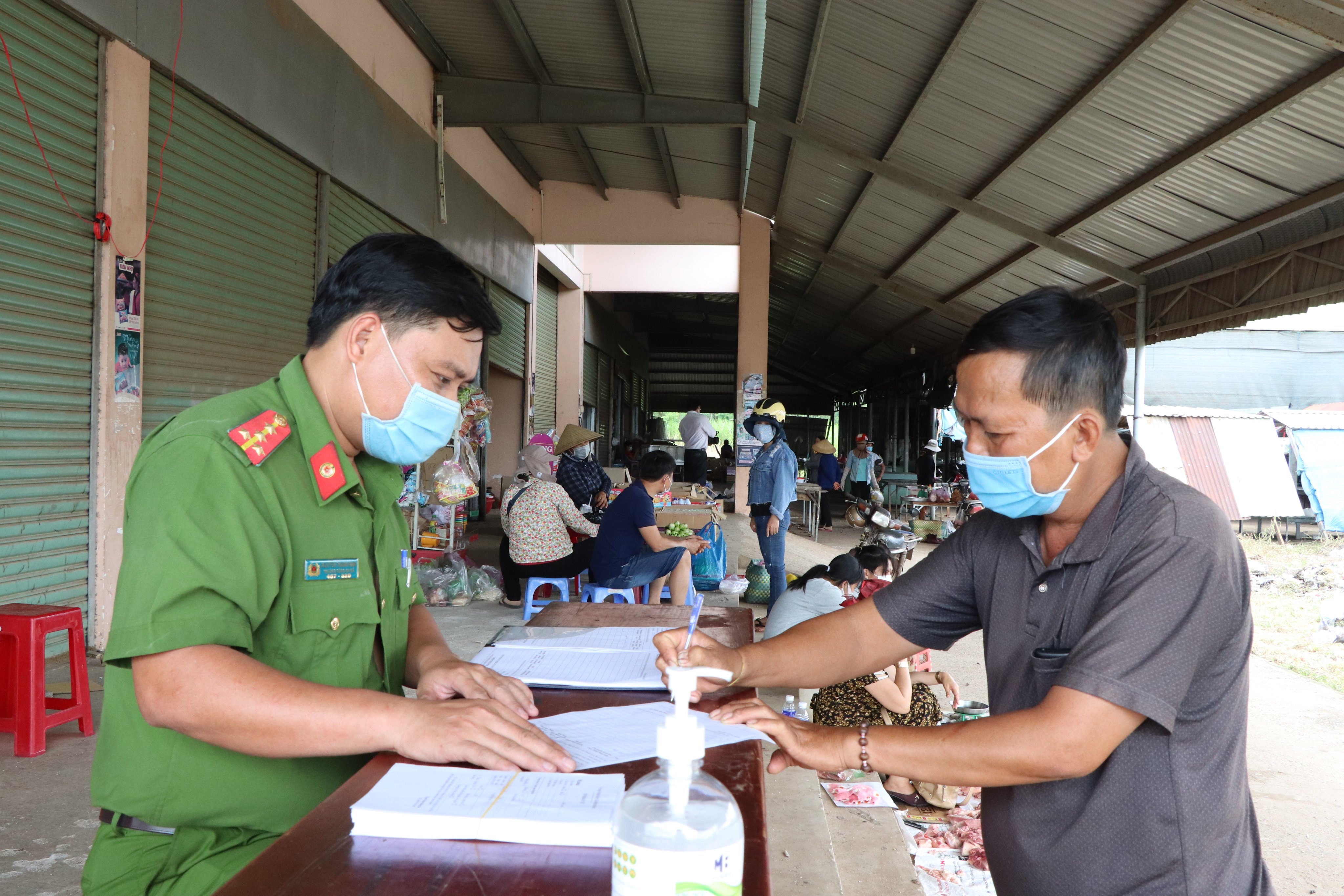 Đại úy Nguyễn Thành Nam, Trưởng Công an xã Bình Trung (huyện Châu Đức) hướng dẫn tiểu thương Hồ Văn lộc (thôn 2, xã Bình Trung) khai báo y tế.