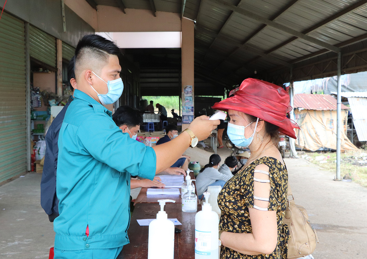 Lực lượng chức năng xã Bình Trung kiểm tra thân nhiệt người dân và tiểu thương khi vào chợ Bình Trung.