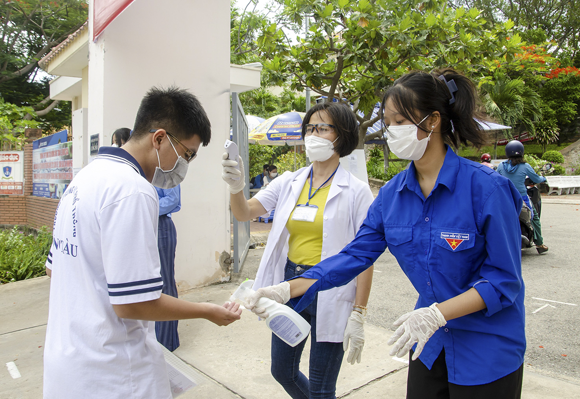 Thí sinh đến điểm thi Trường THPT Vũng Tàu tuân thủ việc đo thân nhiệt, rửa tay sát khuẩn trước khi bước vào khu vực làm thủ tục thi.