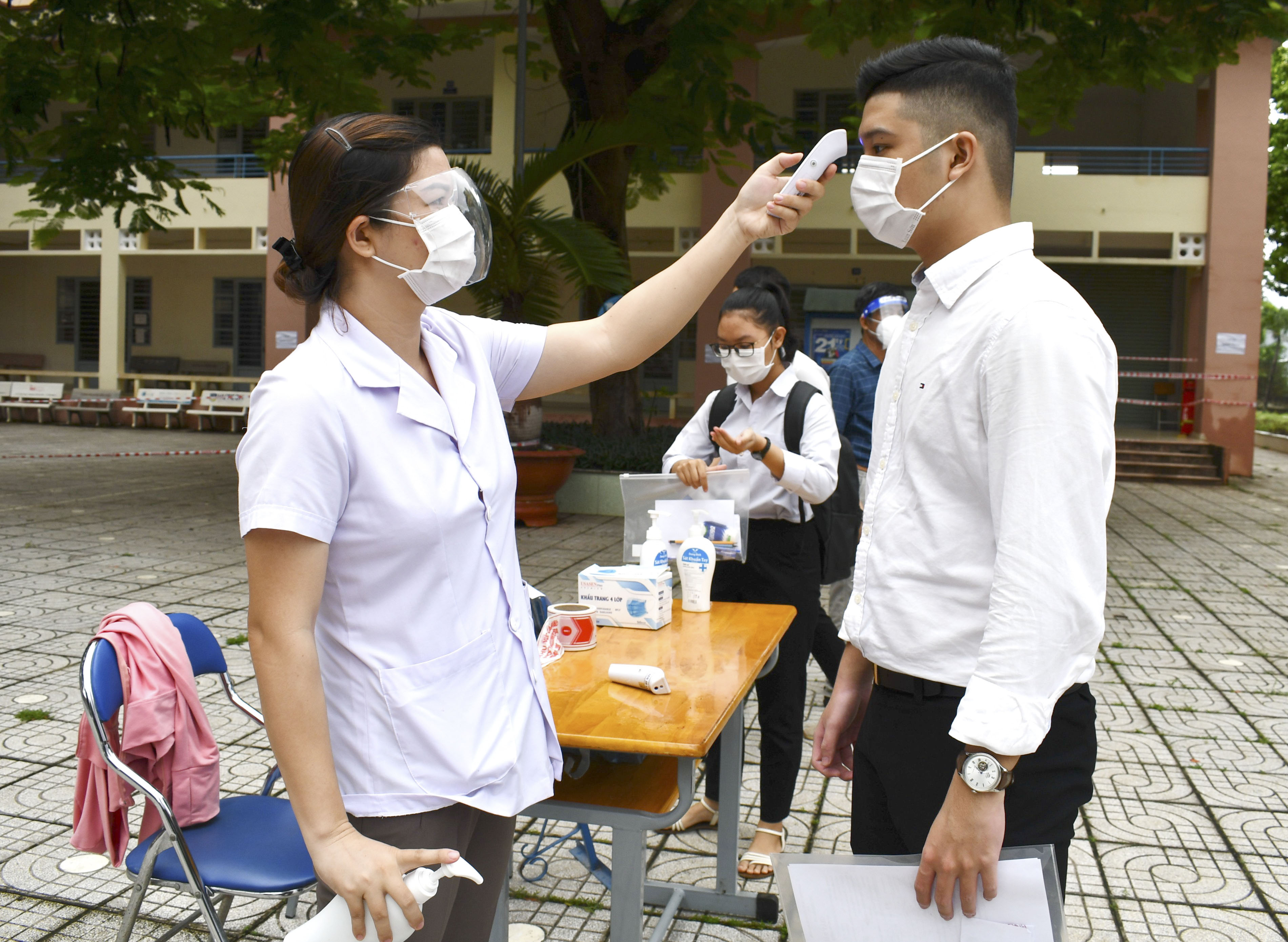 Nhân viên y tế đo thân nhiệt cho TS Trường THPT Nguyễn Trãi (huyện Châu Đức) trước khi vào phòng thi.