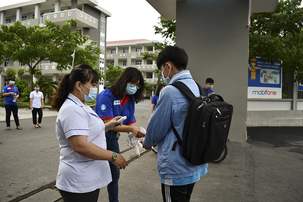 Lực lượng làm nhiệm vụ tại điểm thi Trường THPT Võ Thị Sáu, huyện Đất Đỏ đo thân nhiệt và giúp TS rửa tay sát khuẩn trong ngày thi thứ 2 của kỳ thi TN THPT. ảNH: HUYỀN TRANG