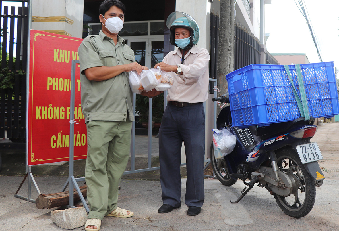 Ông Nguyễn Hoàng Khánh, Chủ tịch Hội CTĐ xã Phước Hưng trao các suất cơm trưa miễn phí đến lực lượng trực chốt tại Tổ 12, ấp Phước Thọ.