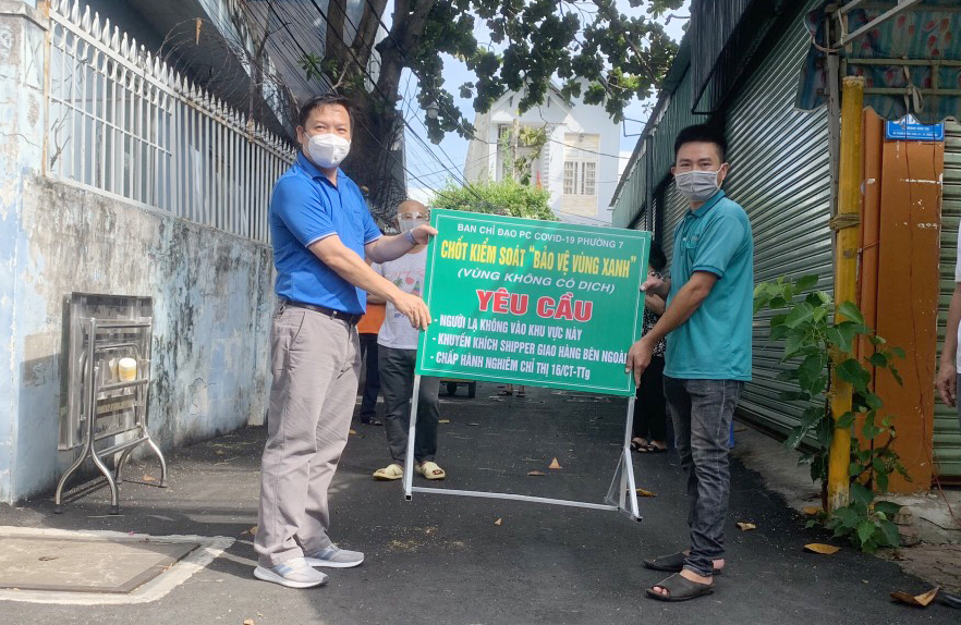 Ông Nguyễn Xuân Thanh (trái), Chủ tịch UBND phường 7 đặt bảng “Chốt vùng xanh - vùng không có dịch” tại hẻm 82 Phạm Hồng Thái.