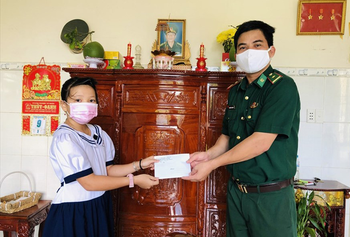 Thiếu tá Nguyễn Văn Năng, Bí thư Đảng ủy, Chính trị viên Đồn Biên phòng Côn Đảo trao học bổng cho em Nguyễn Thị Anh Thư (lớp 5, Trường TH Cao Văn Ngọc, huyện Côn Đảo).