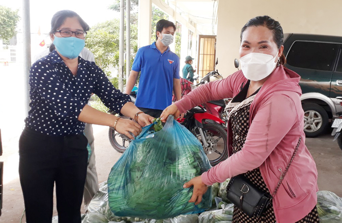 Bà Phạm Thị Miến (bìa phải) chuyển rau đã mua hỗ trợ nông dân xã Châu Pha cho đại diện phường Tân Phước.