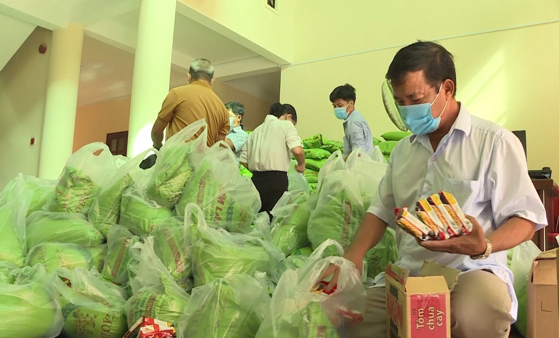 Cán bộ, công chức huyện Đất Đỏ sắp xếp nhu yếu phẩm chuẩn bị trao cho người dân trong khu phong tỏa,  hộ nghèo, hộ có hoàn cảnh khó khăn trên địa bàn thị trấn Phước Hải chiều 26/8. Ảnh: TUẤN VŨ
