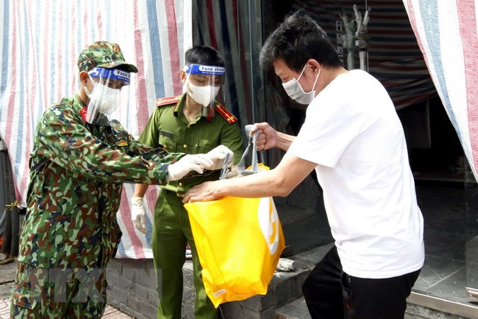 Cán bộ chiến sĩ Trung đoàn 1, Sư đoàn 9, Quân đoàn 4 cùng cảnh sát khu vực phường Võ Thị Sáu, Quận 3 (TP. HCM) trao túi hỗ trợ cho những người ở trọ có hoàn cảnh khó trong những ngày thành phố giãn cách xã hội “ai ở đâu, ở yên đấy.” Ảnh: TTXVN