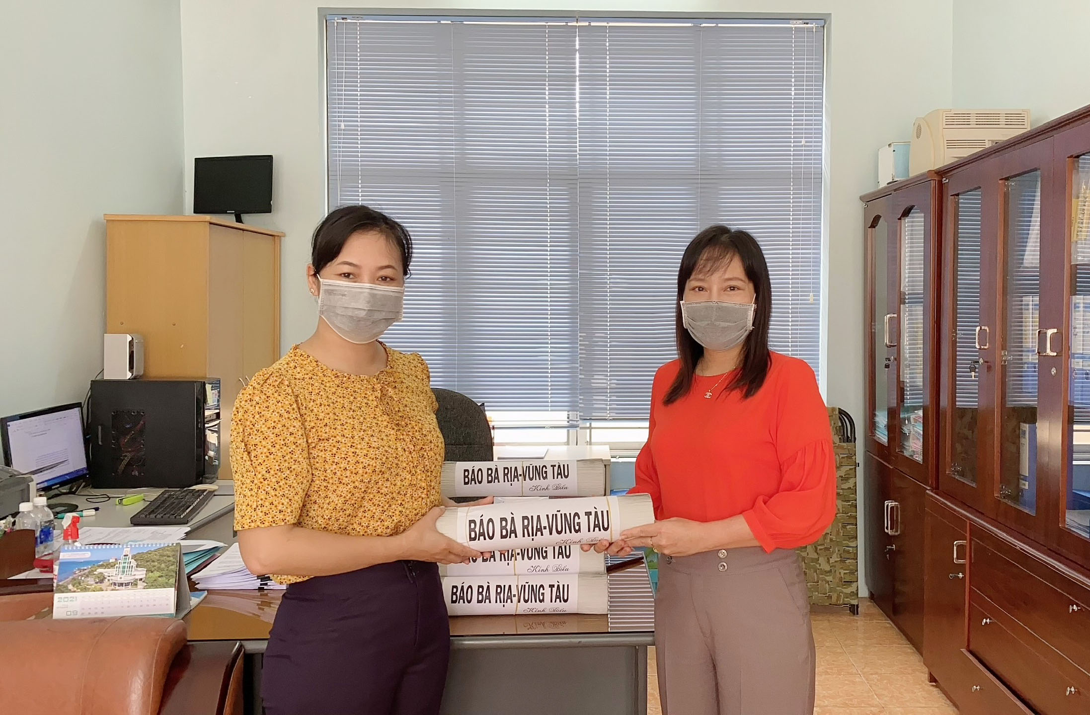 Bà Đỗ Nguyễn Hoàng Dung (phải), Quyền Tổng Biên tập Báo Bà Rịa - Vũng Tàu trao báo cho bà Nguyễn Thị Hồng Khuyên, Phó Ban Tuyên giáo TX. Phú Mỹ