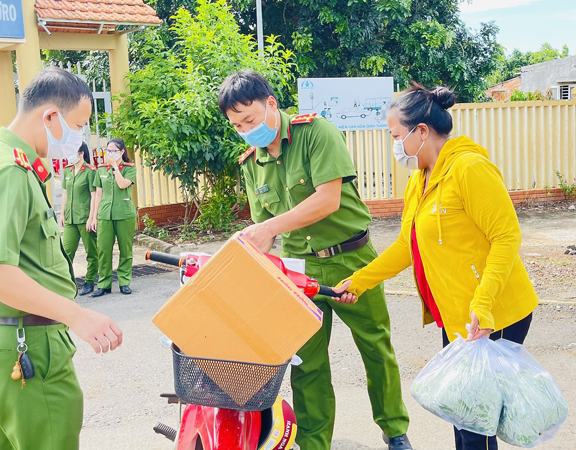 Cán bộ, chiến sĩ Phòng Cảnh sát Điều tra tội phạm về ma túy chuyển quà lên xe máy để người dân chở về nhà.