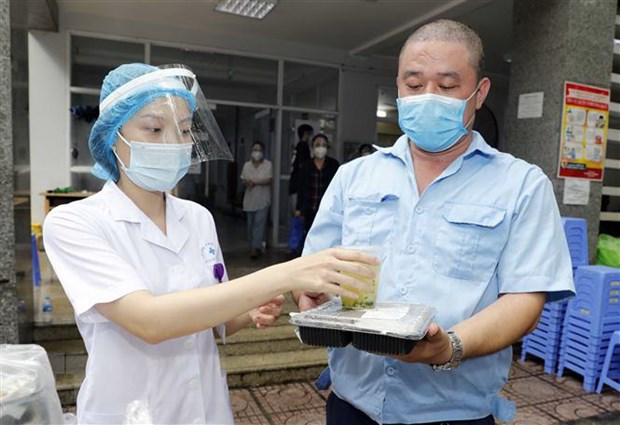 Đại diện lực lượng tuyến đầu chống dịch quận Hai Bà Trưng, Hà Nội đón nhận bữa trưa từ nhà hảo tâm. Ảnh: TTXVN