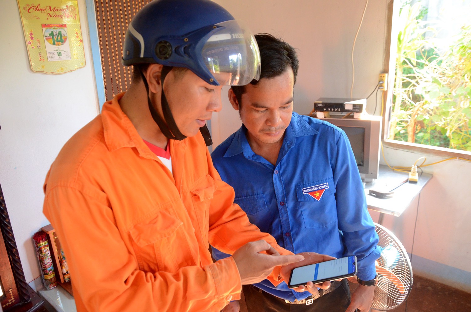Nhân viên điện lực Bà Rịa - Vũng Tàu hướng dẫn khách hàng sử dụng app CSKH của ngành điện lực.Ảnh: VÂN ANH