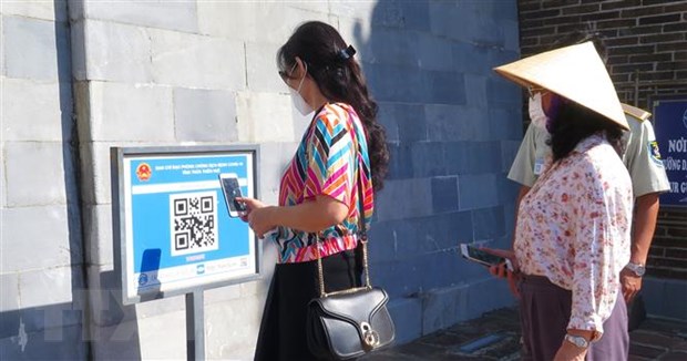 Du khách quét mã QR Code trước khi vào tham quan các điểm di tích tại Huế. (Ảnh: Tường Vi/TTXVN)