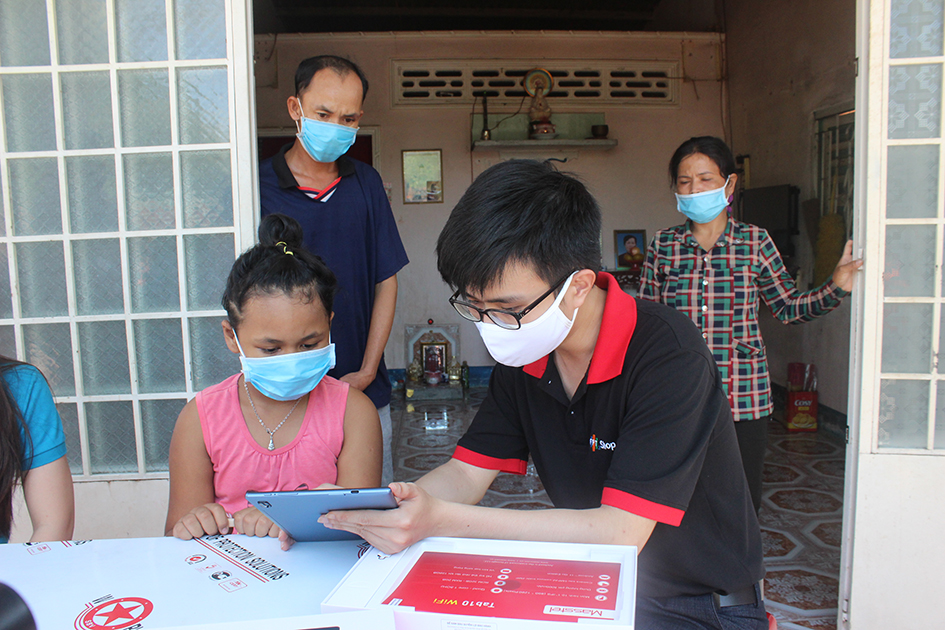 Đại diện Công ty CP FPT hướng dẫn em Trần Thạch Yến Linh cách sử dụng máy tính bảng để học trực tuyến.