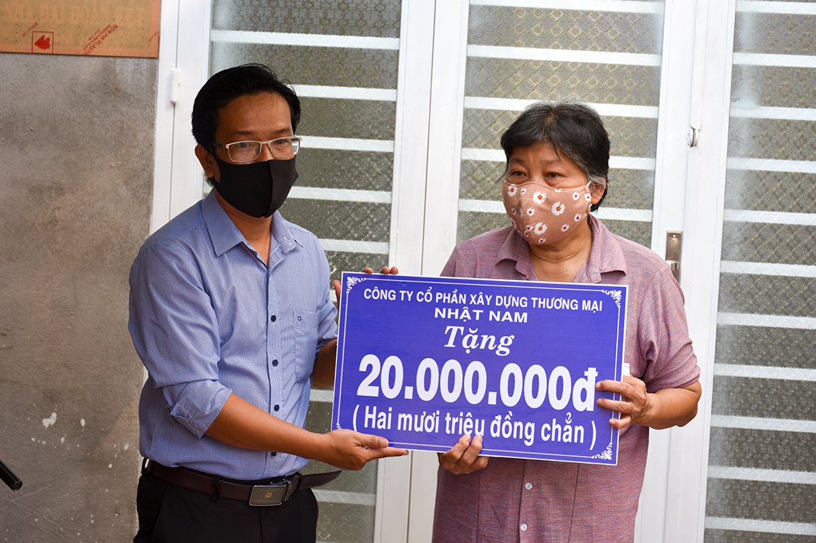 Đại diện Công ty CP Xây dựng thương mại Nhật Nam tặng 20 triệu đồng cho bà Trần Ngọc Xinh, vợ ông Bùi Hoàng Sang (phường Phước Nguyên).
