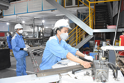 Các DN đã nhanh chóng cho người lao động vào guồng công việc ngay từ ngày đầu năm. Trong ảnh: Công nhân Công ty CP kỹ thuật cửa Huynh Đệ sử dụng máy ép góc để sản xuất cửa nhôm.