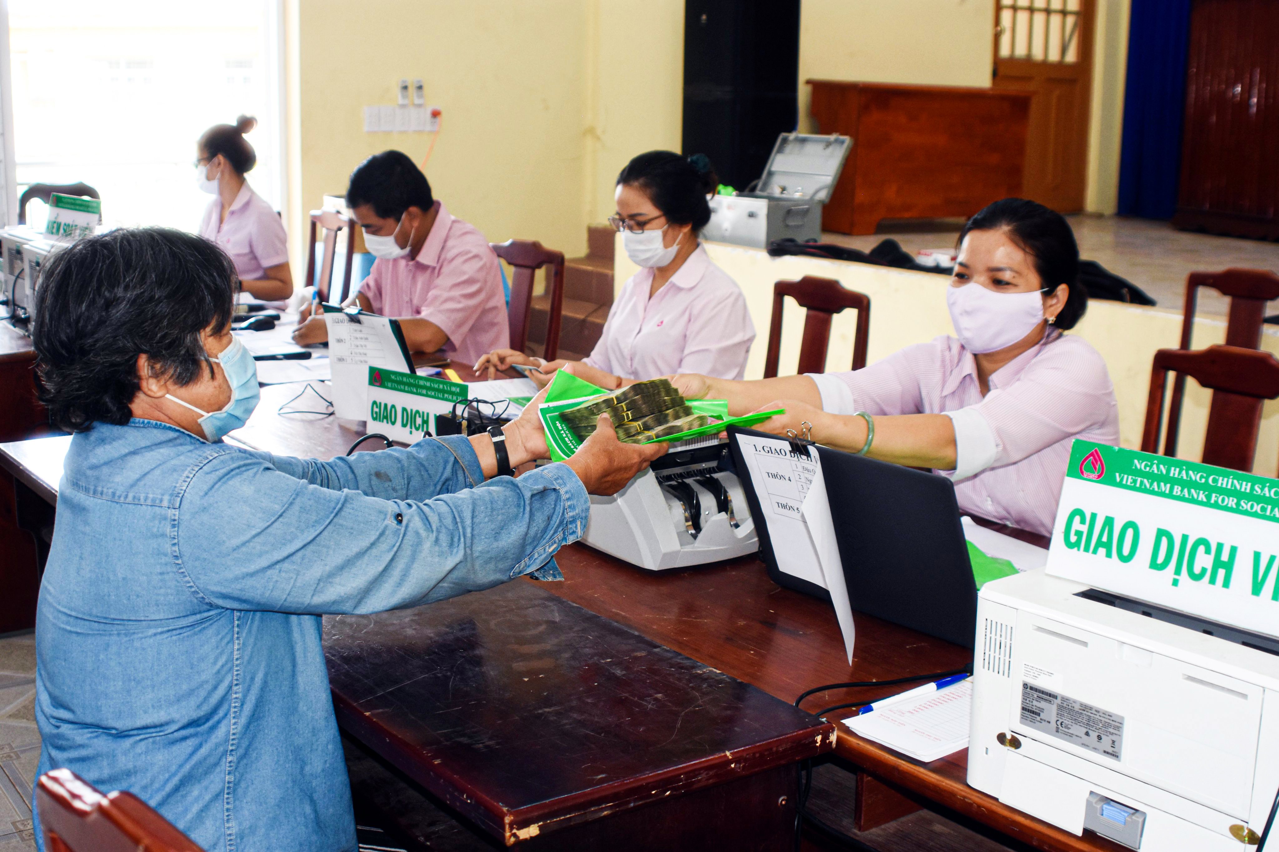Nhân viên Phòng Giao dịch NHCSXH huyện Châu Đức trao tiền giải ngân vốn vay cho người dân xã Bình Giã.