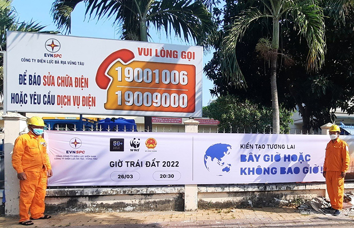 Nhân viên Điện lực Vũng Tàu treo băng rôn tuyên truyền Giờ Trái đất 2022 trước trụ sở.