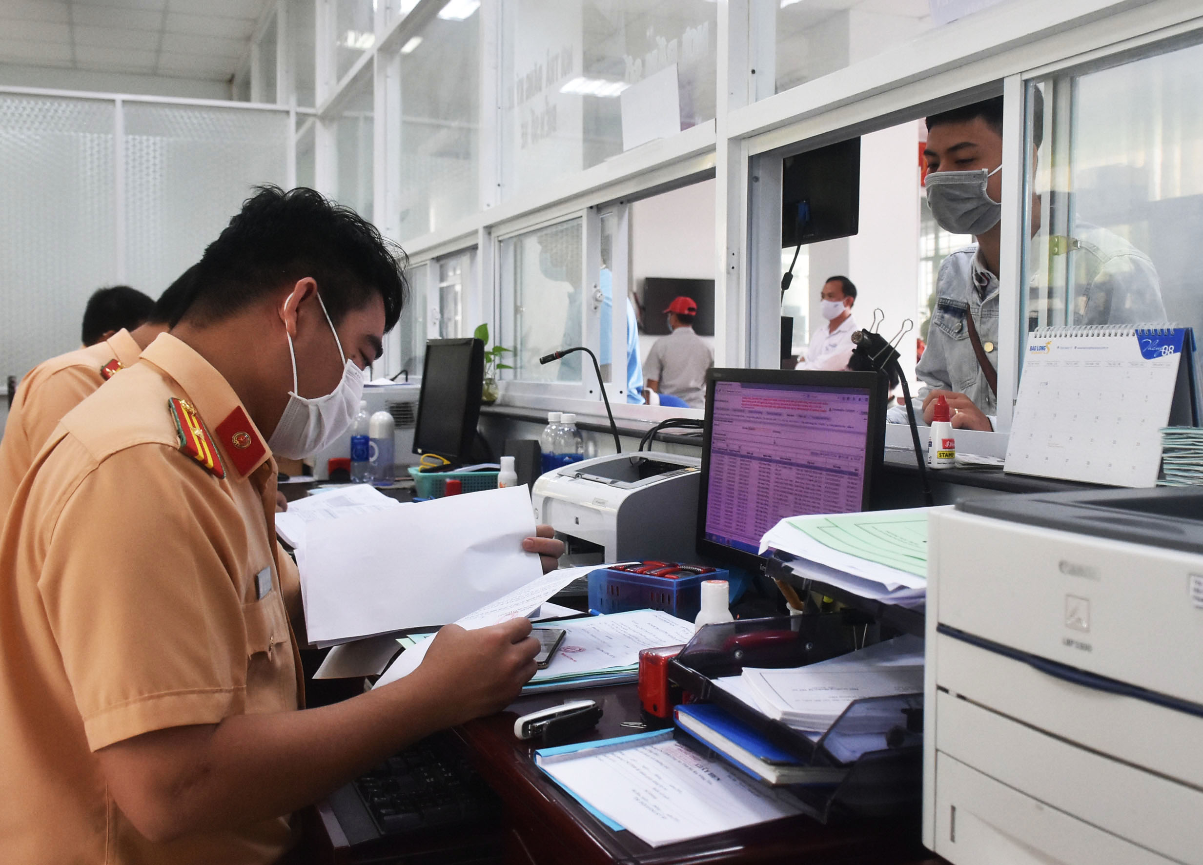 Cán bộ Phòng CSGT, Công an tỉnh xem xét hồ sơ cấp biển số xe cho người đăng ký phương tiện.